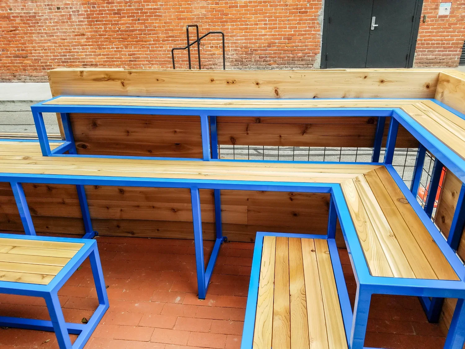 Tiered wooden outdoor seating offers adaptable spaces for sitting and eating, along woth movable benches.