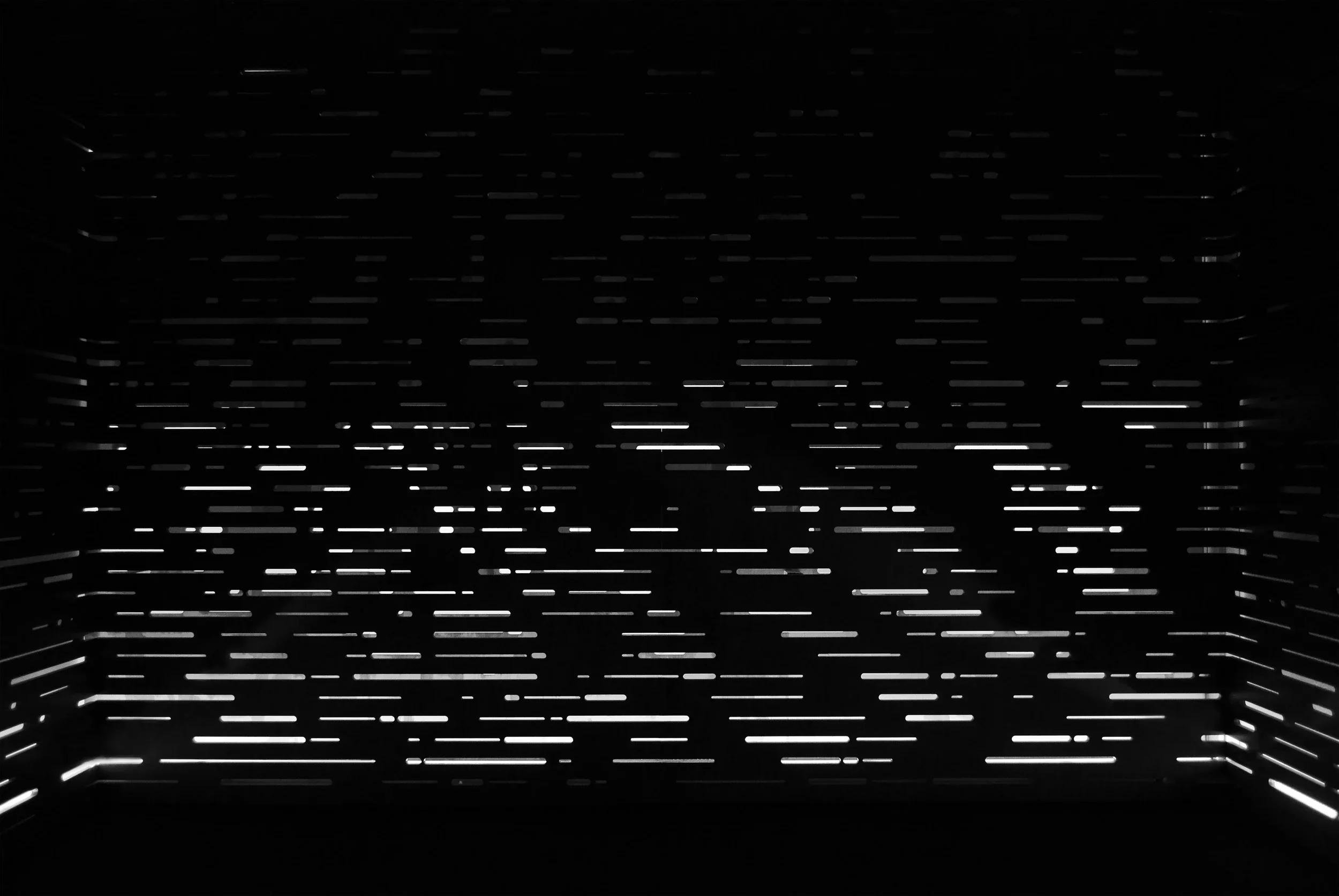 A dark room with evenly spaced horizontal cavities, backlit, creates a trippy, mesmerizing space.