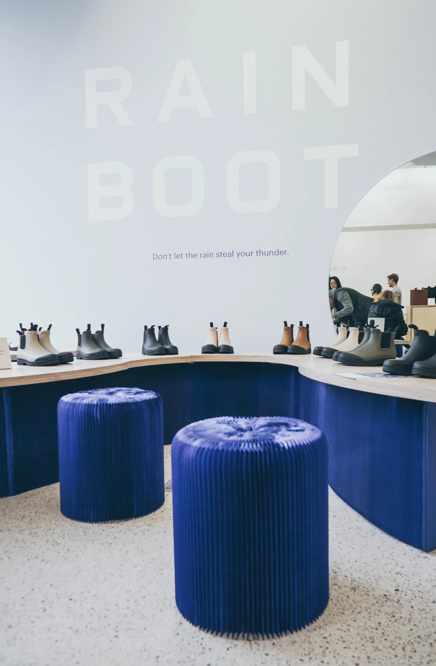 Boots are displayed on a weaving custom-milled wood surface, with seating to try the boots on in the foreground.