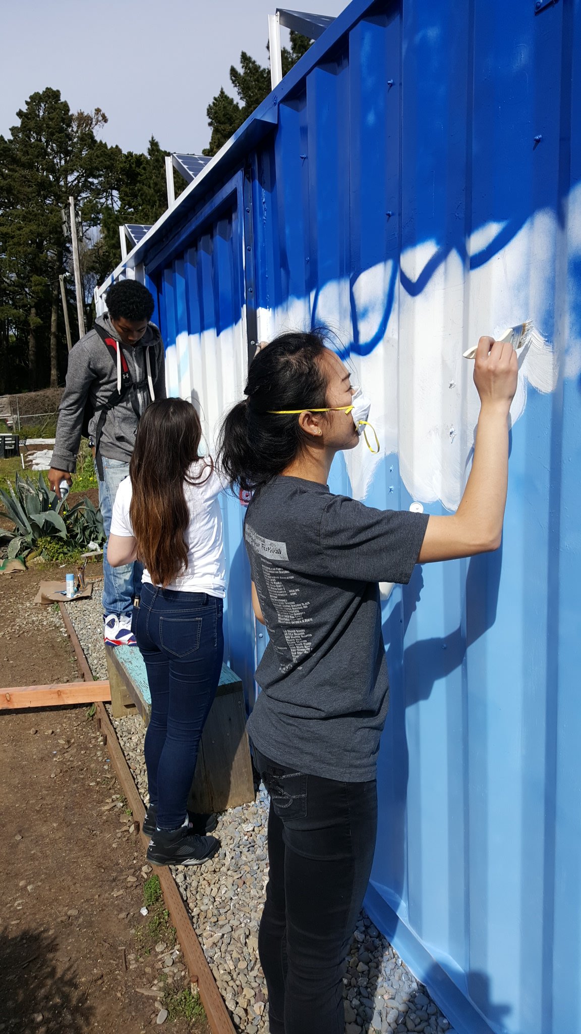 People painting the mural, wearing masks for safety.