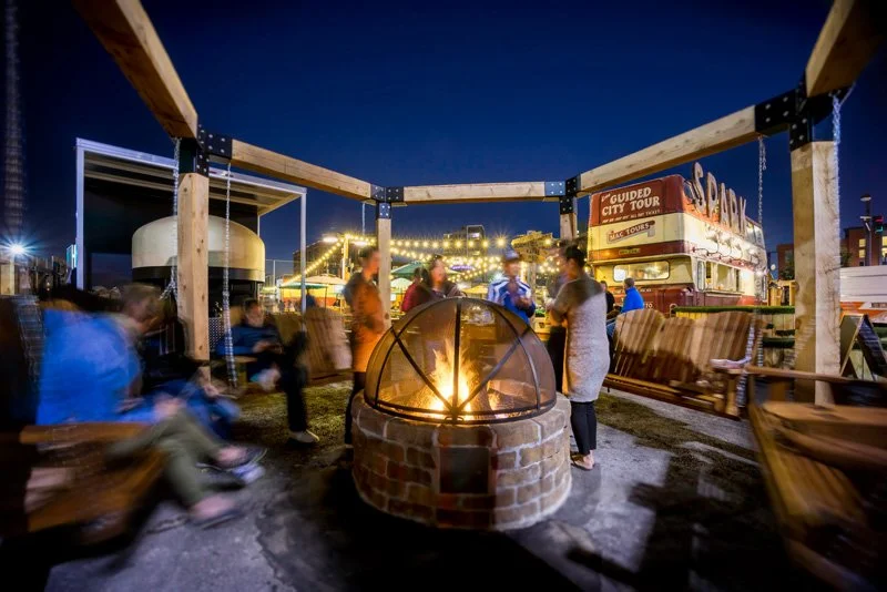 The hearth is an age-old tool for gathering. An enclosed firepit welcomes patrons to sit around a custom pergola with swinging wooden benches.