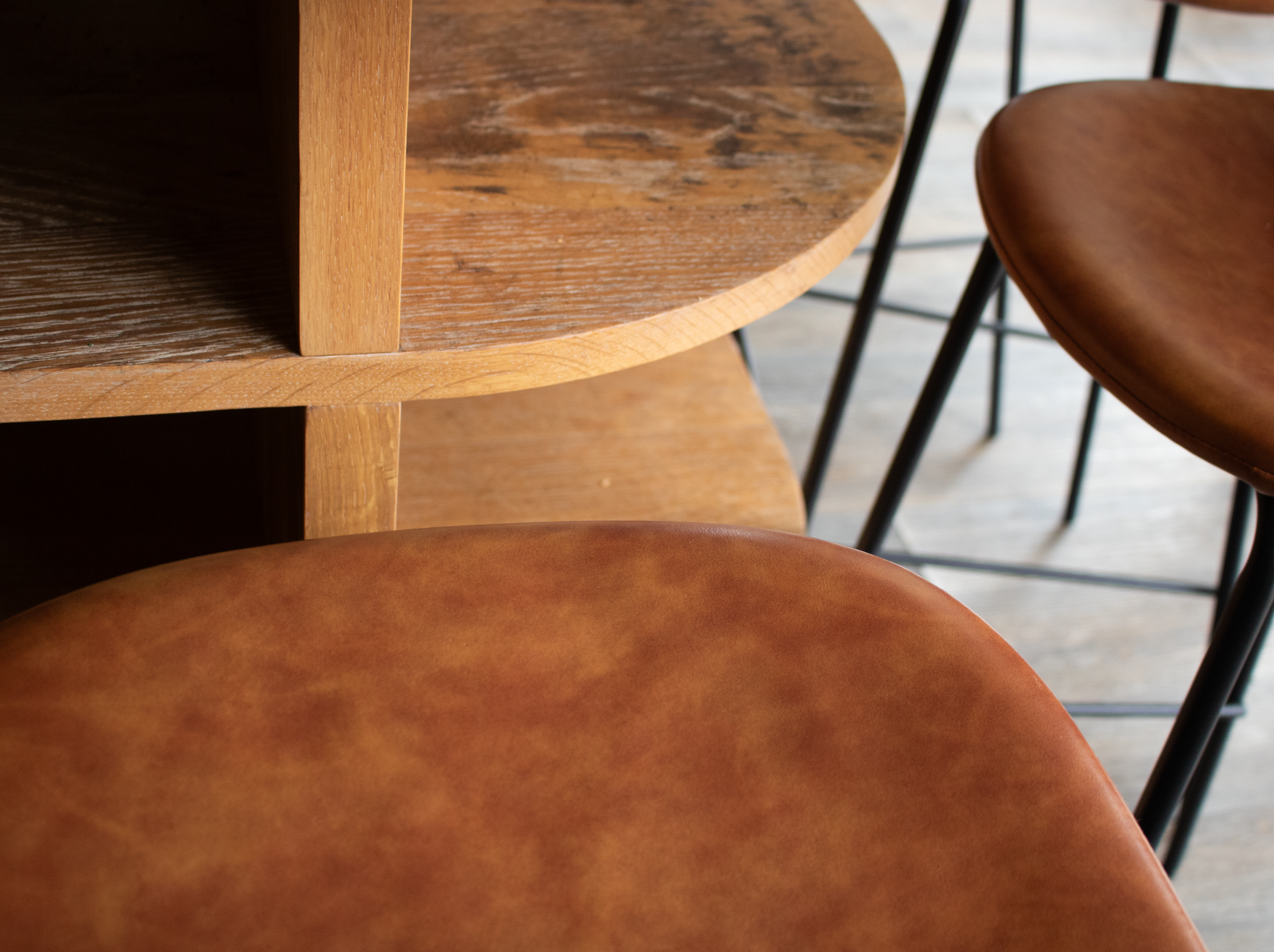 Close-up of round wooden shelves with brown leather chairs.