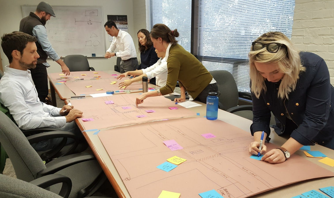 People working together on a large project laid out on a table, using sticky notes and markers in a conference room