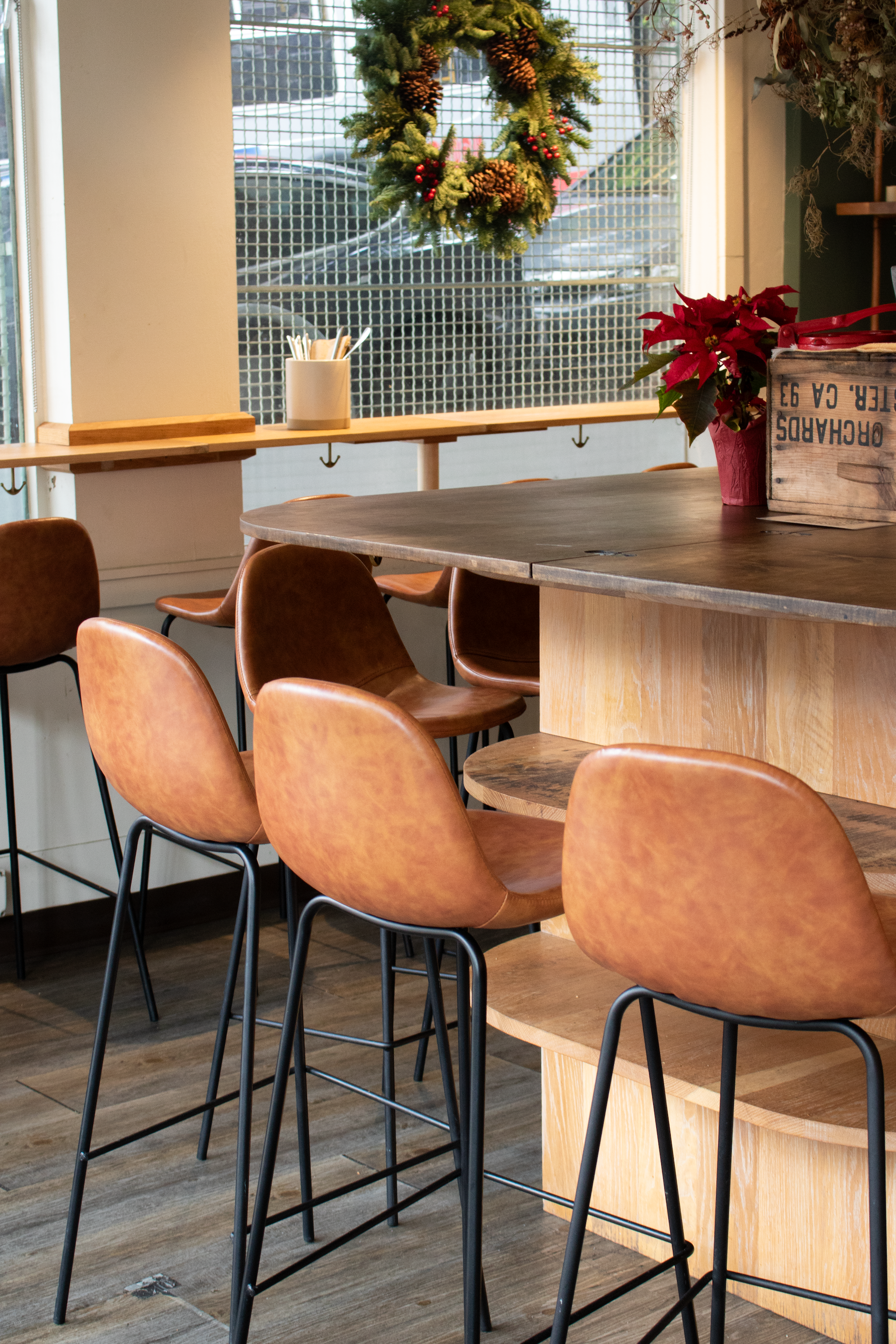 A bar countertop is lined by leather and metal chairs. The countertop is decorated for Christmas.
