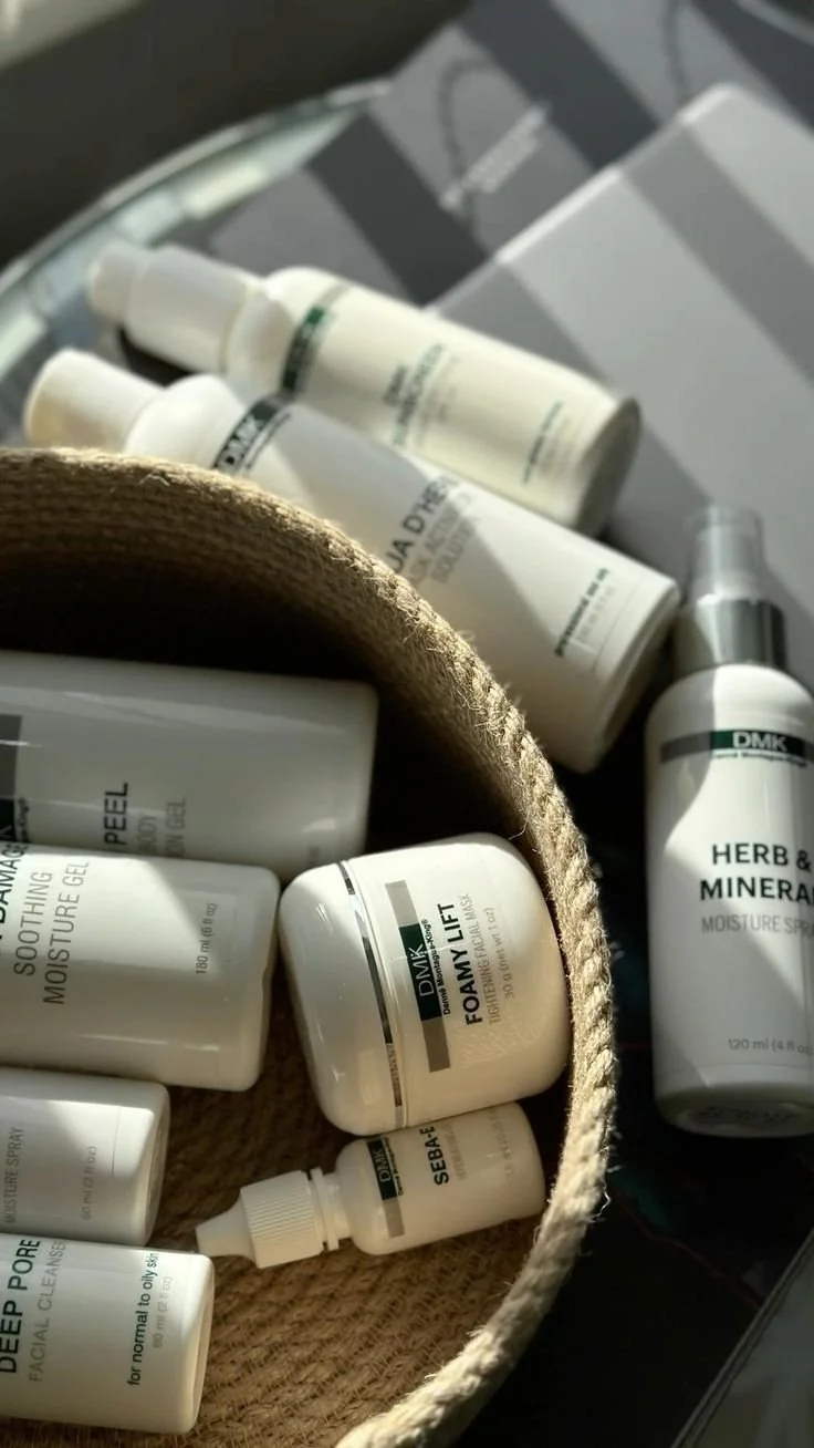 Collection of skincare and beauty products, including creams, gels, and sprays, with some placed in a woven basket and others on a surface.