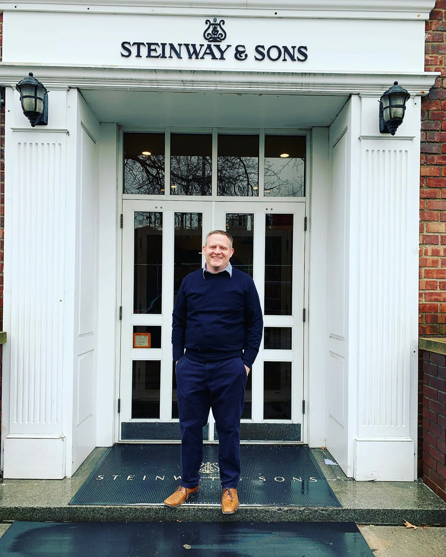 Brandon Bascom in front of the entrance to the Steinway & Sons headquarters in Queens, New York