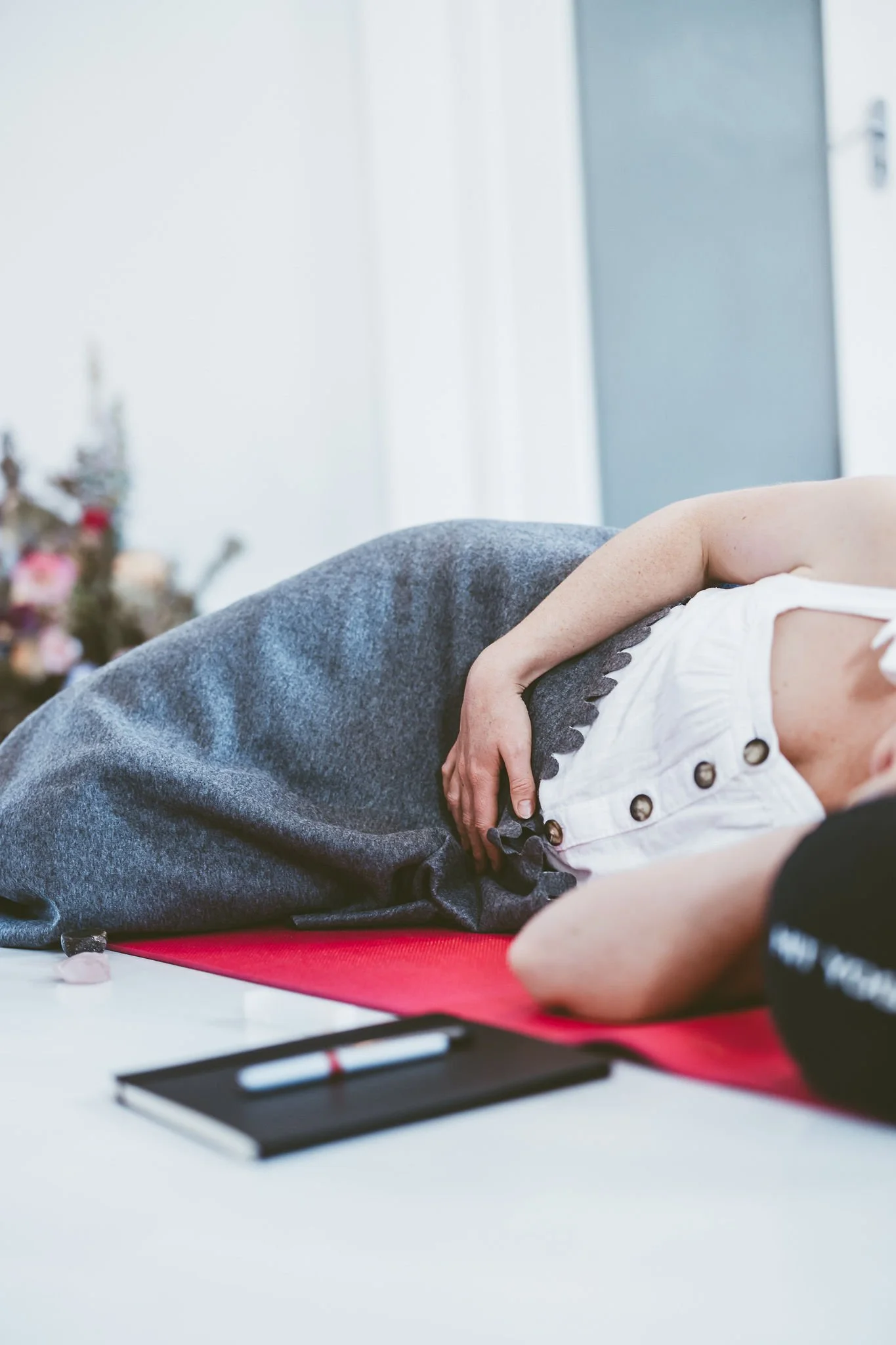 A person lying on their side on a red mat, appearing to be in labor or experiencing discomfort, with a pen and notepad nearby.