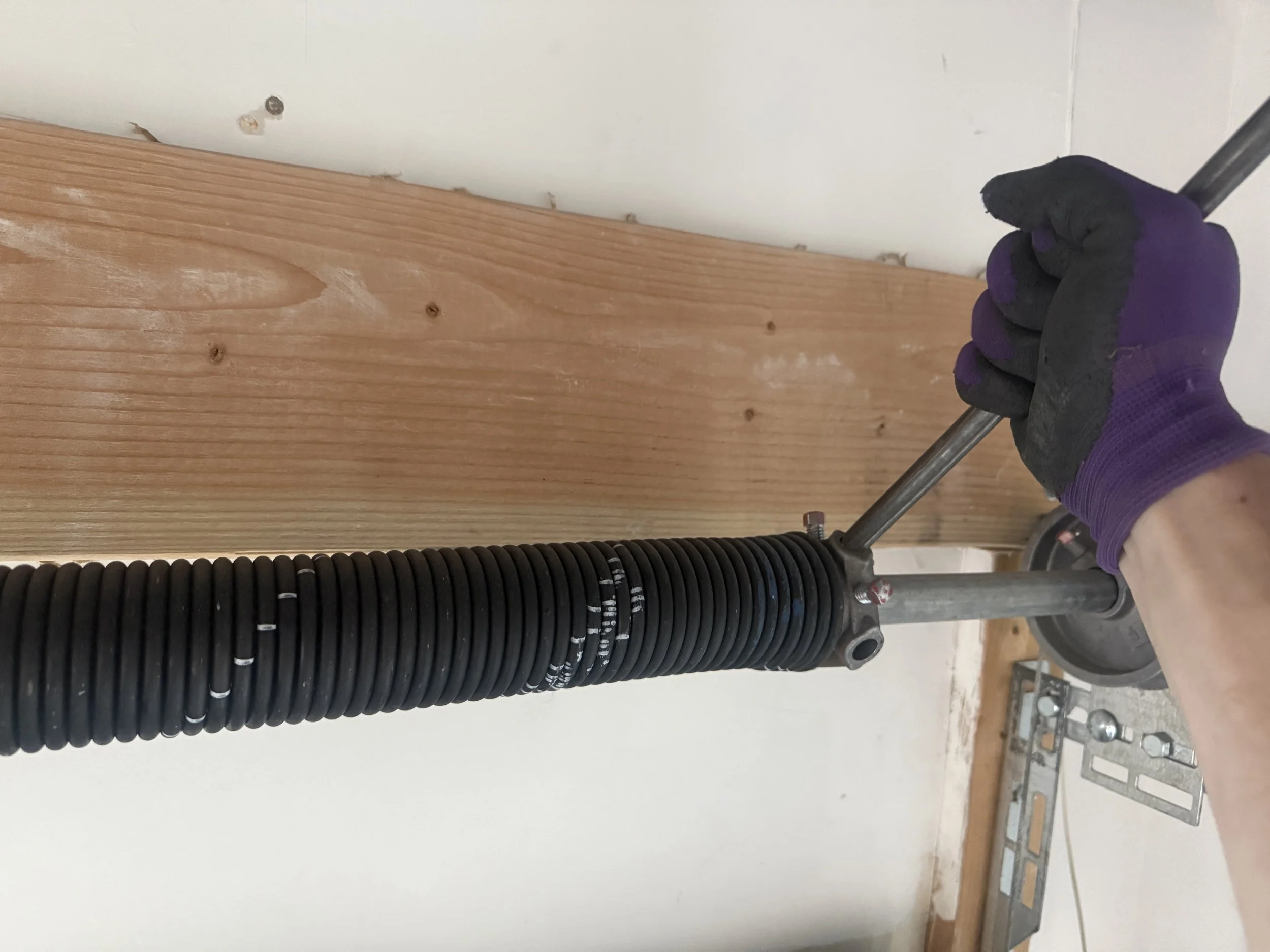 Garage door spring replacement in Utah showing a torsion spring being adjusted