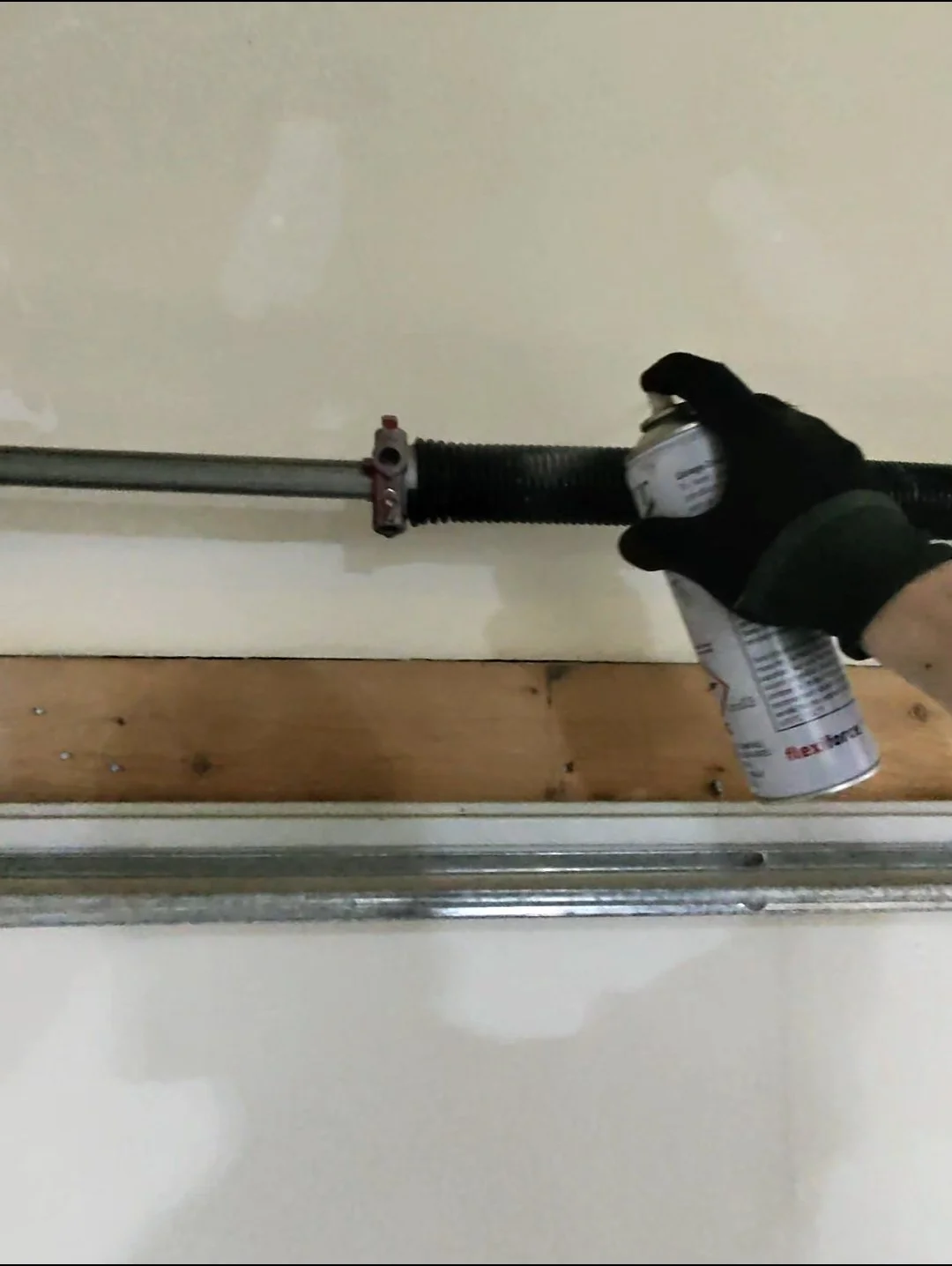 Garage door spring being lubricated during a tune-up