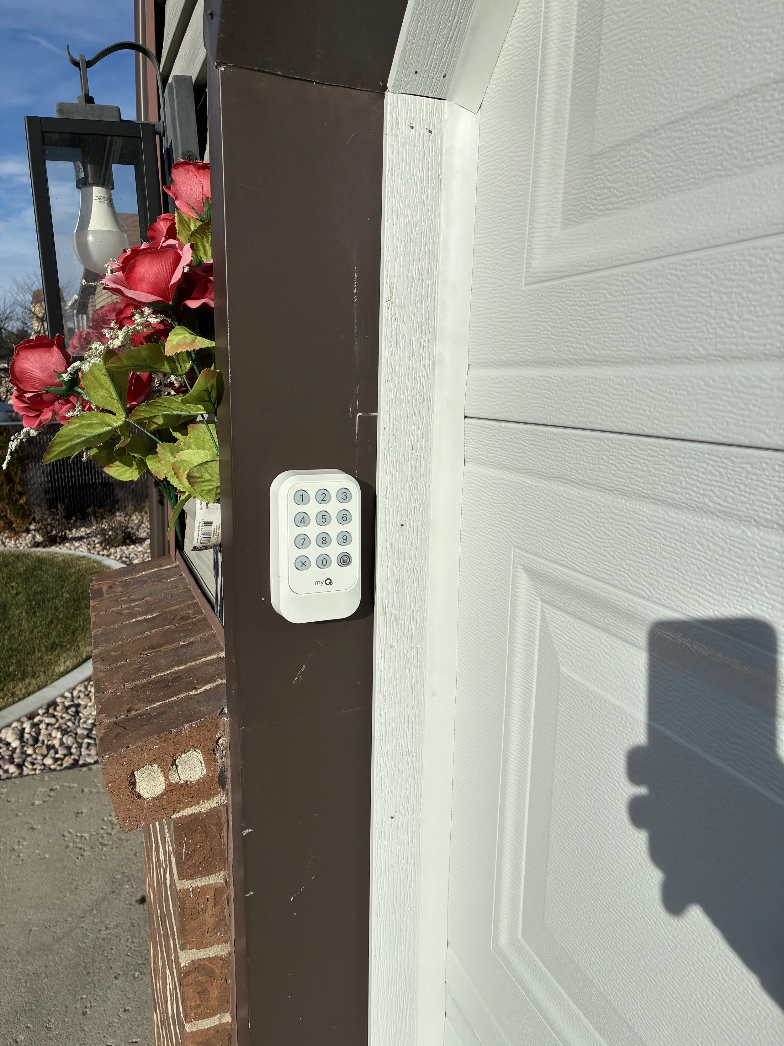 Wireless garage door opener keypad installed beside a residential garage door