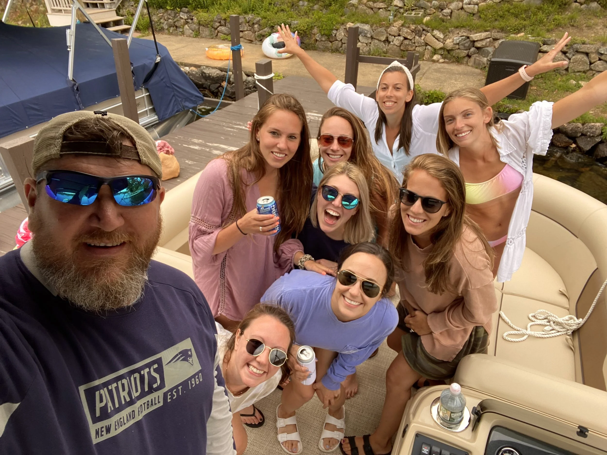 Group of friends on a boat enjoying a sunny day, smiling, and posing for a group photo.