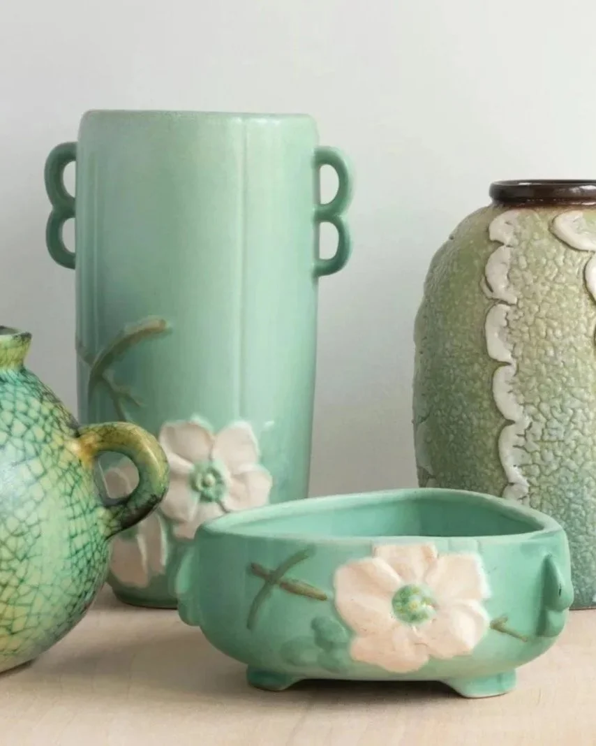 Collection of ceramic vases and bowls with pastel green and yellow glazes, decorated with floral and textured patterns.