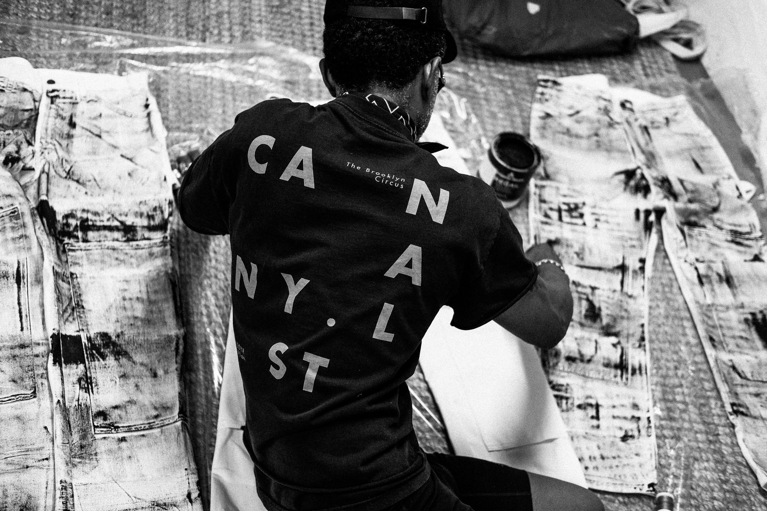 Person painting or creating art on large paper sheets, seated on a textured mat, surrounded by art supplies.