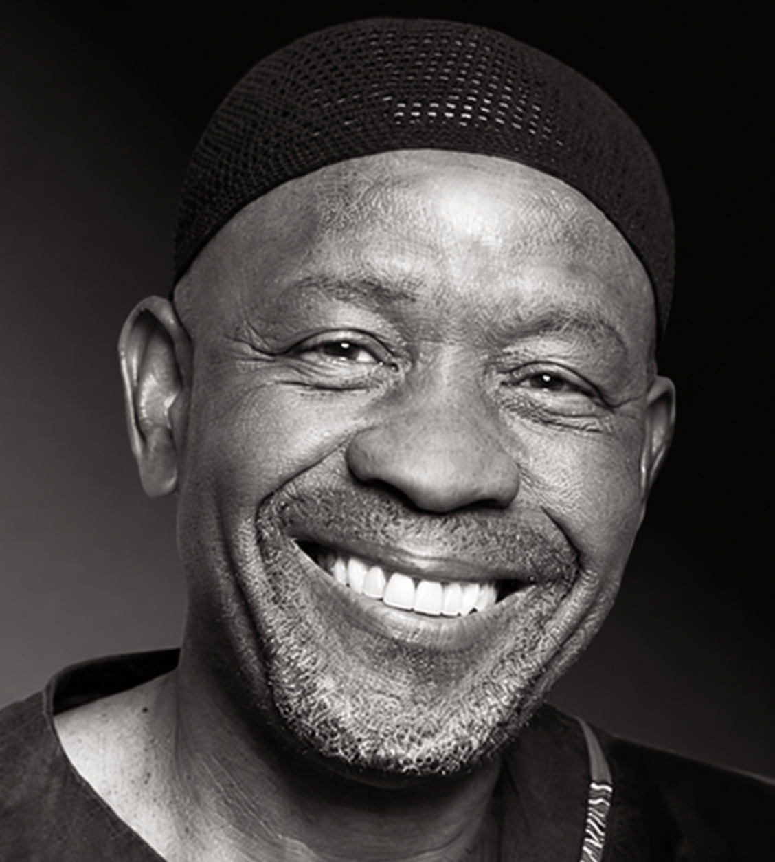 Black-and-white portrait of composer Caiphus Semenya smiling and wearing a dark cap.