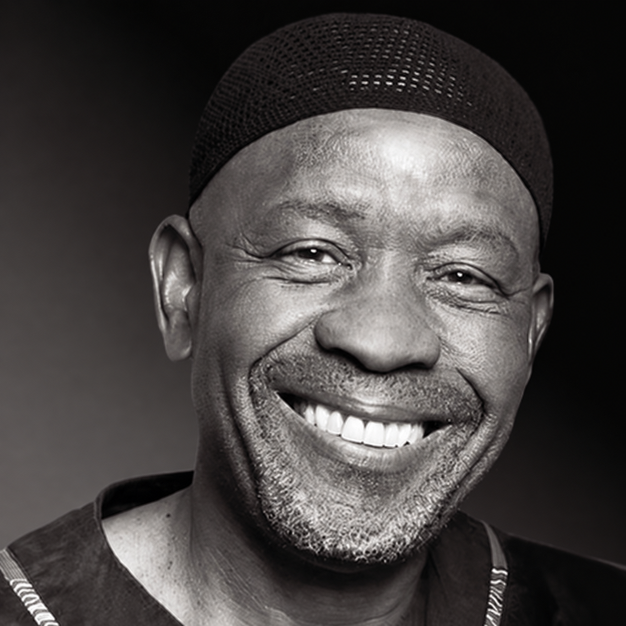 Black-and-white portrait of Caiphus Semenya smiling in a dark cap.
