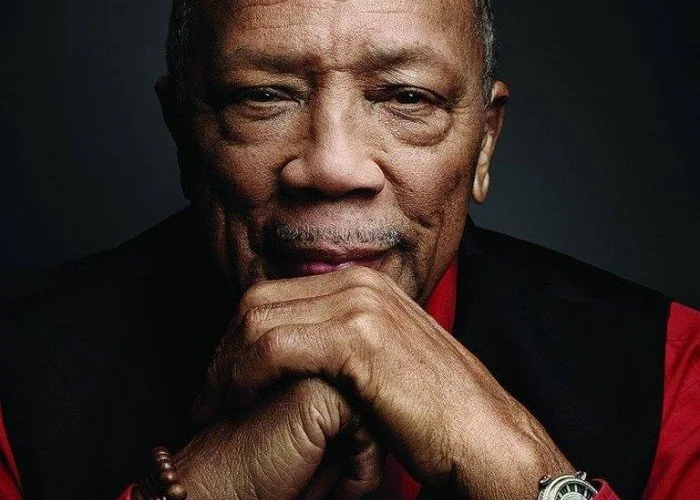 Portrait of Quincy Jones resting his chin on his clasped hands.