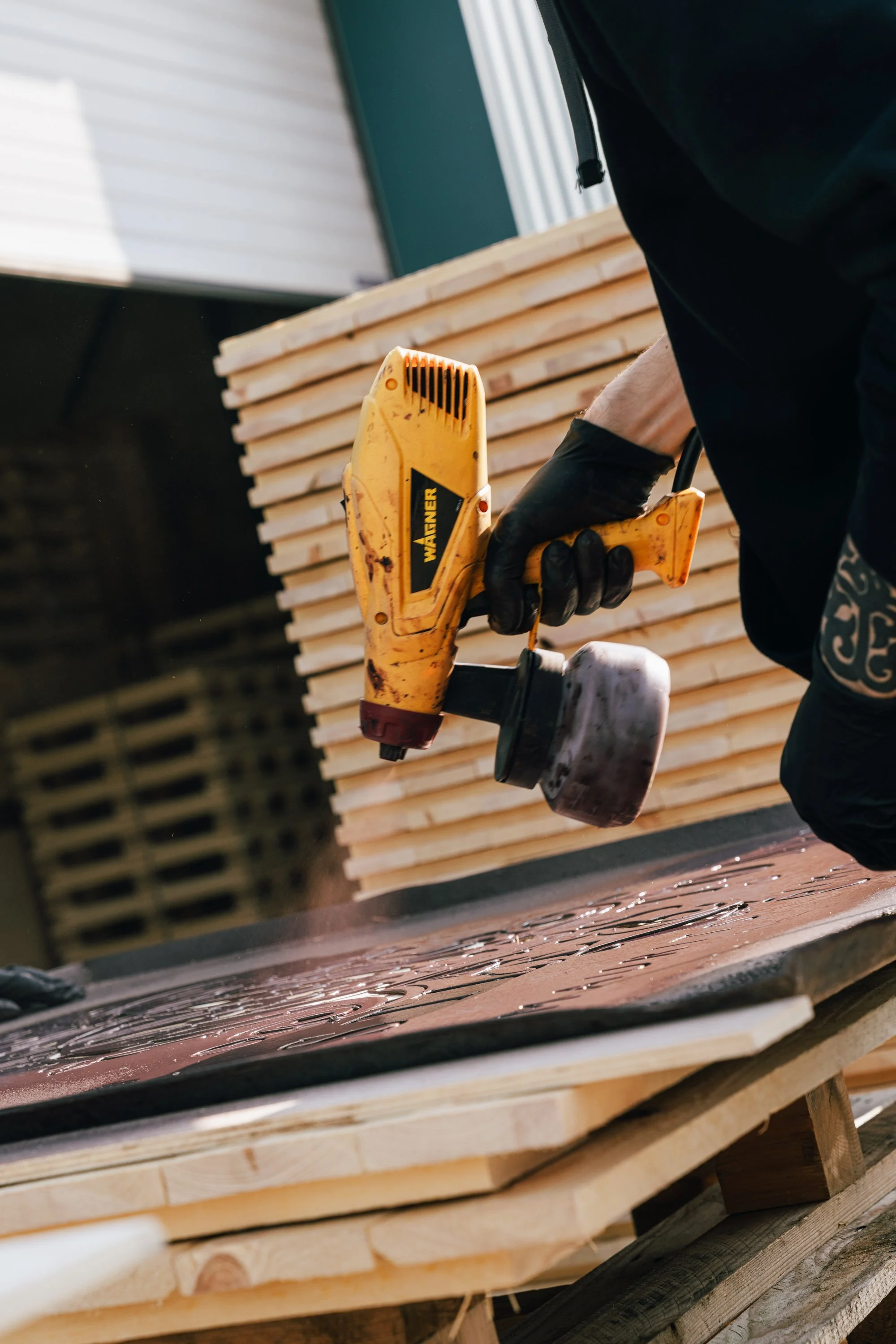 Werknemer van Kistenmakenrij Torremans die met zwarte handschoenen die een gele WAFNER-branded spijkerpistool vasthoudt, om logo's op de kisten te plaatsen