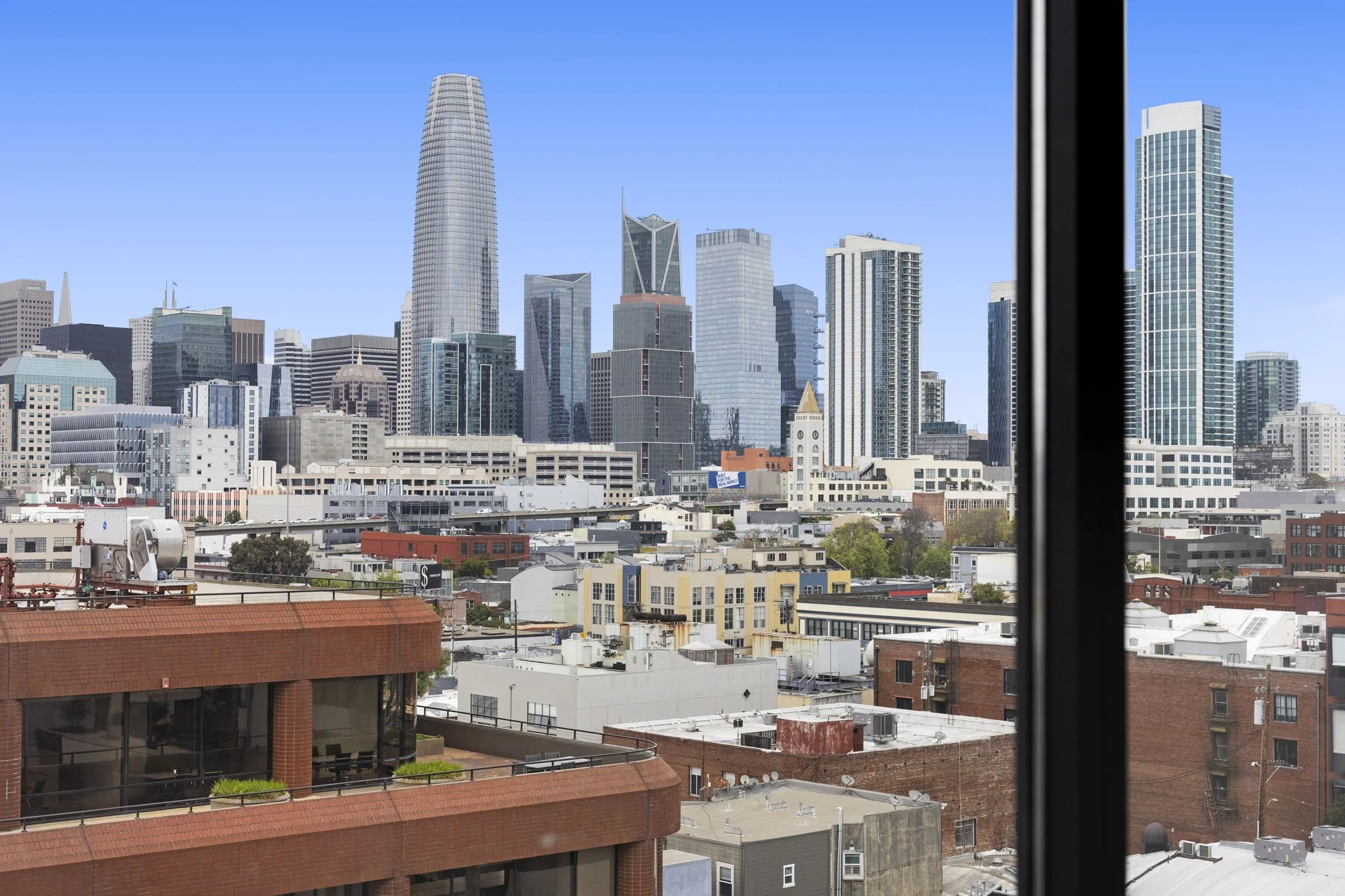 View of San Francisco skyline with tall skyscrapers, including Salesforce Tower, from a window.