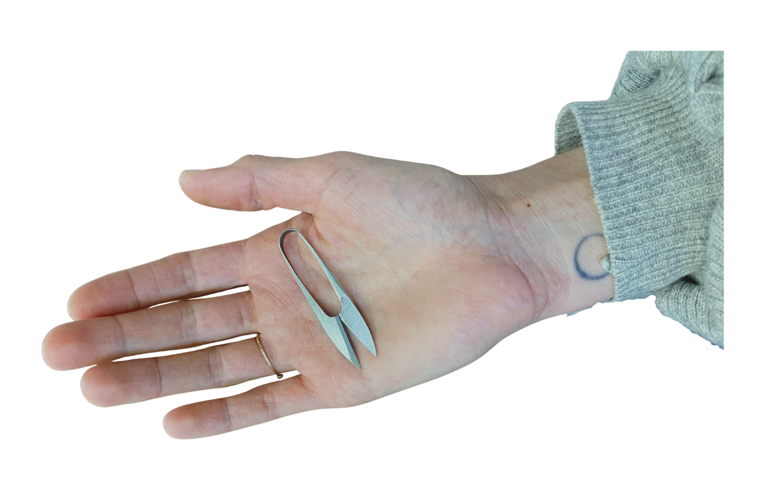 Hand holding a small blue nail clipper with a silver handle, with a tattoo of the letter 'C' on the wrist, wearing a gray sweater.