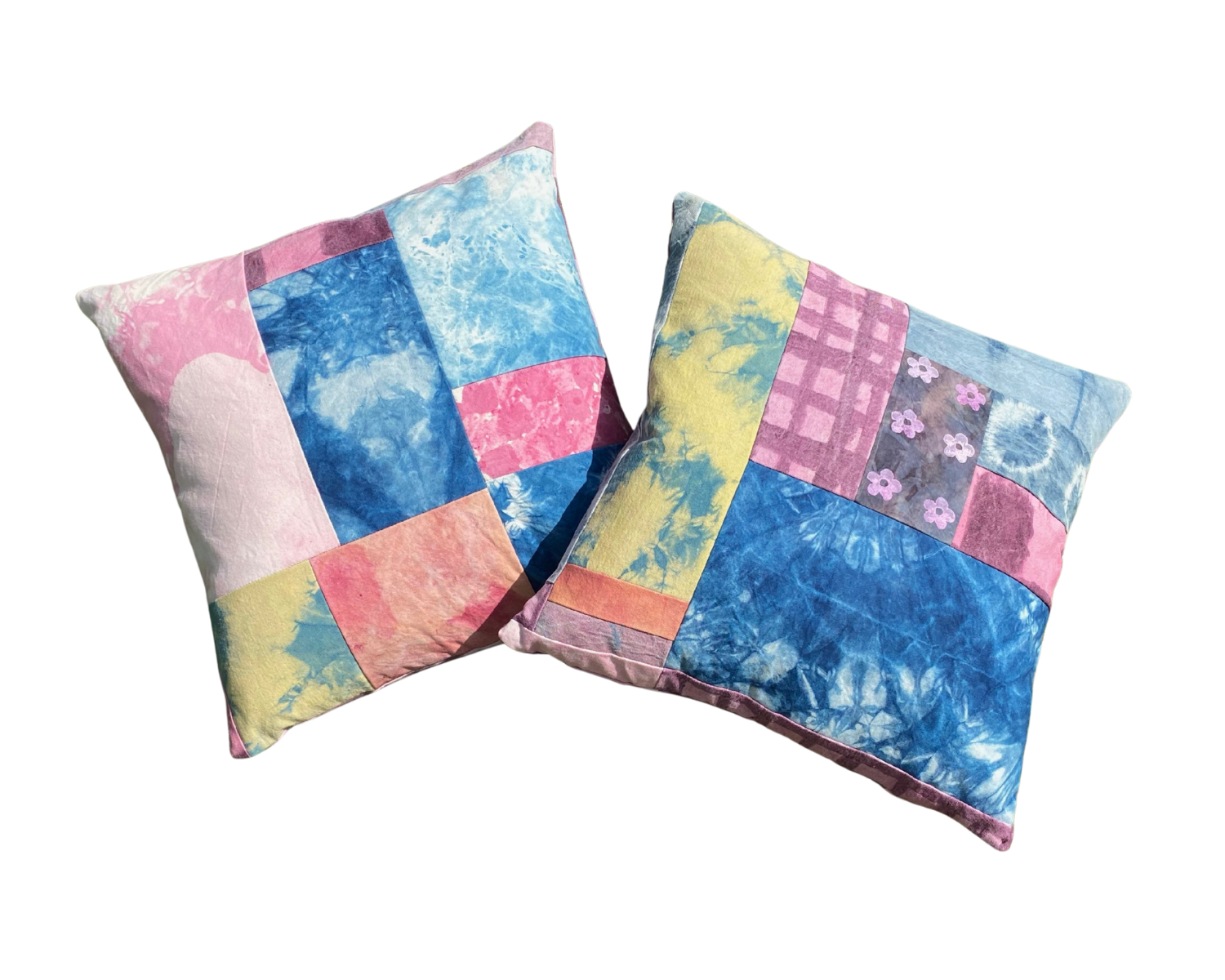 Two patchwork quilted pillows with pastel colors and tie-dye patterns on a black background.