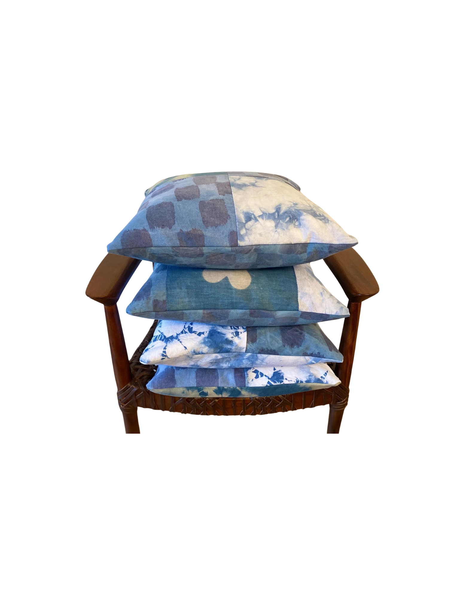 A wooden chair with a woven wicker seat, stacked with four cushions featuring various blue and white floral and abstract patterns.