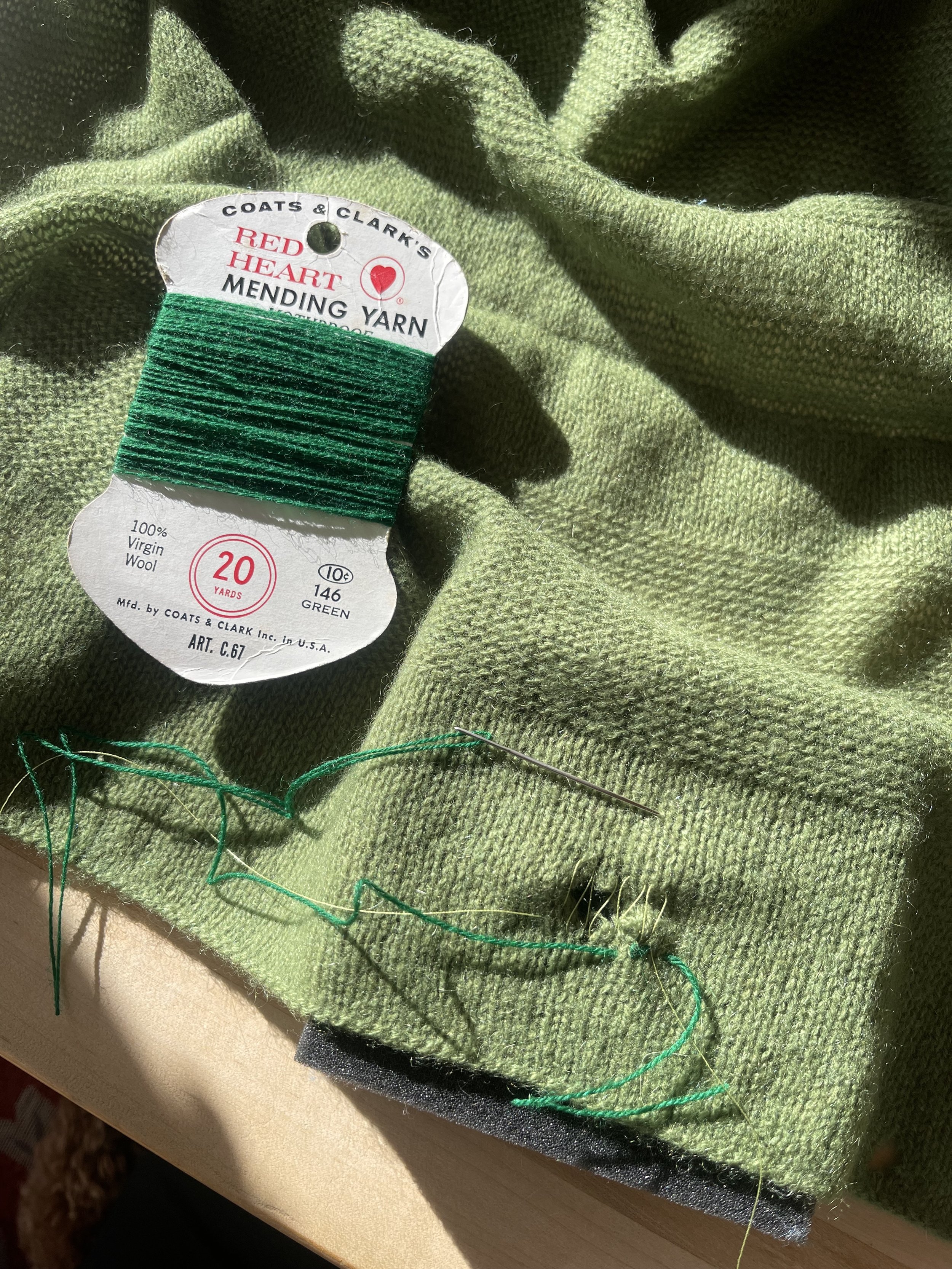 Green fabric with a yarn label and sewing thread.