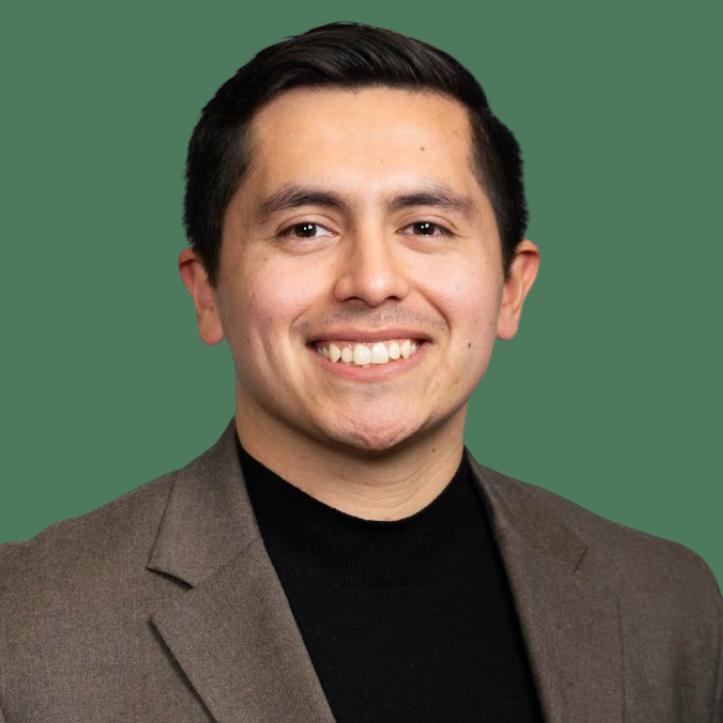 Headshot of smiling male consultant with short black hair wearing a brown blazer.