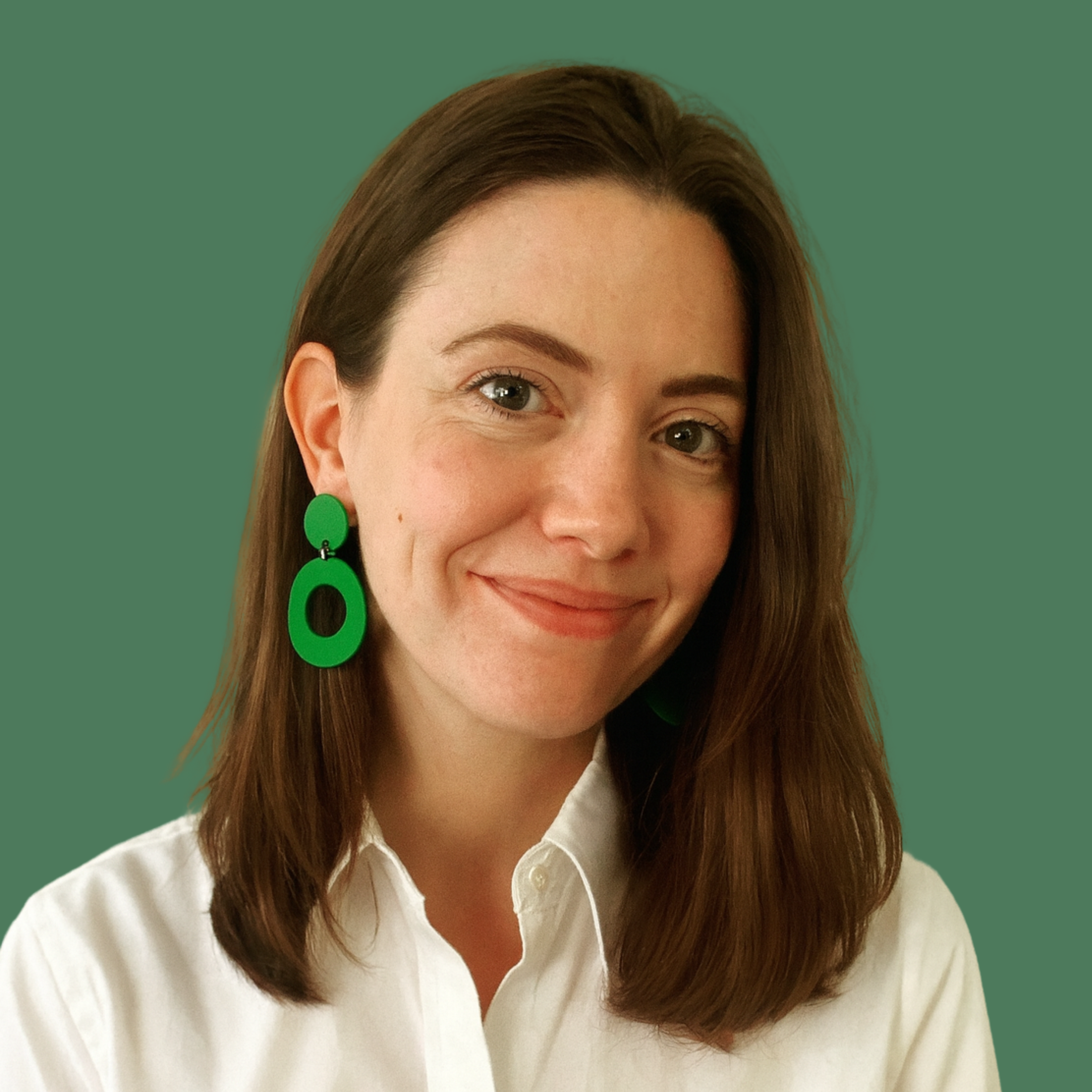 Headshot of smiling female consultant with long brown hair wearing a white shirt and green earrings..