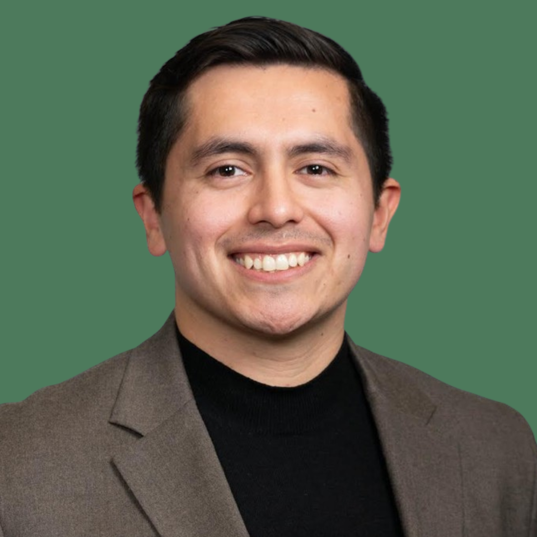 Headshot of smiling male consultant with short black hair wearing a brown blazer.