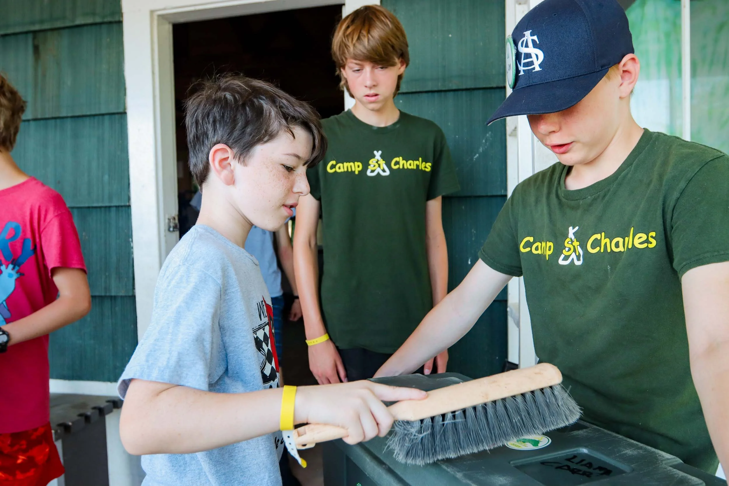 Mentor campers helping a younger camper clean his trunk.