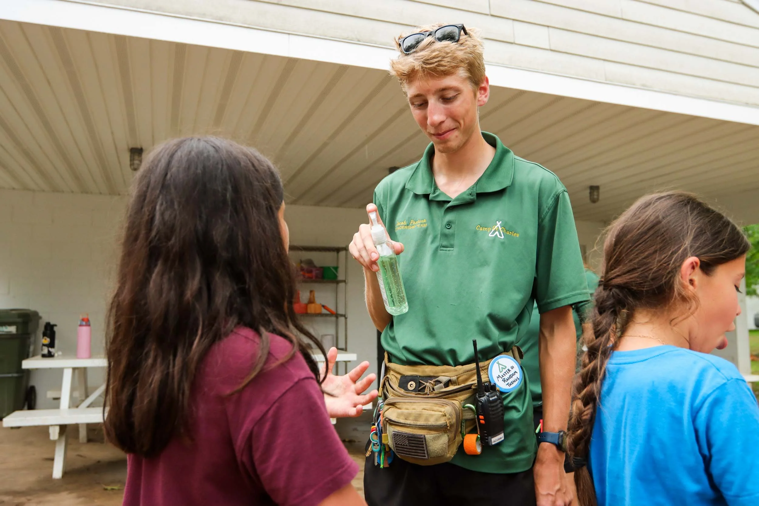 A male counselor giving a camper some hand sanitizer.
