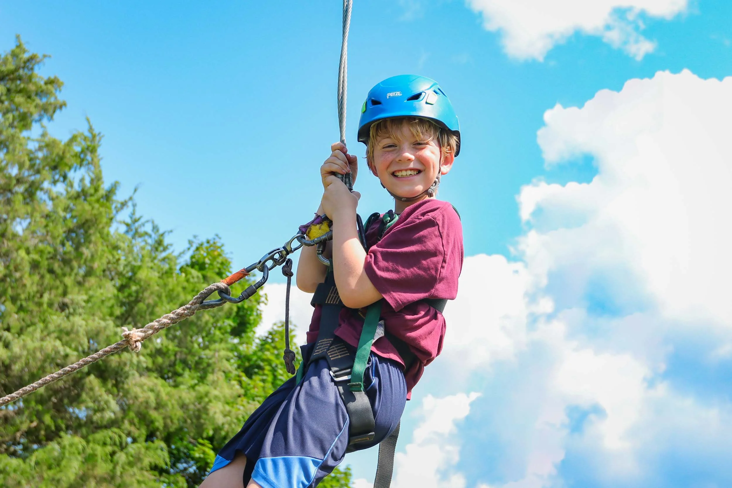 Young boy smiling on a zip line.