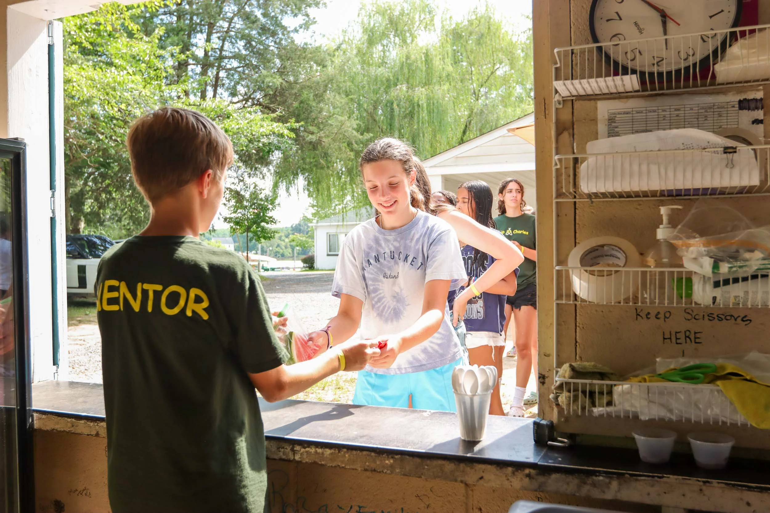 A mentor camper serving other campers at the snack stand.