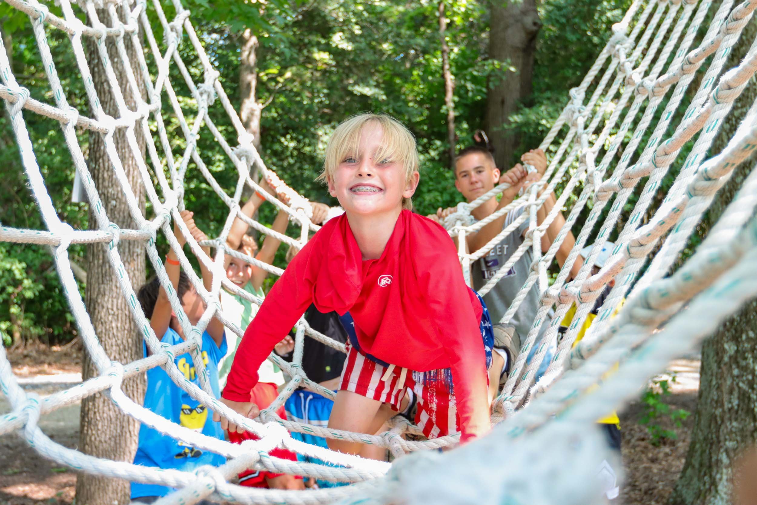 A young boy traversing a ropes course.
