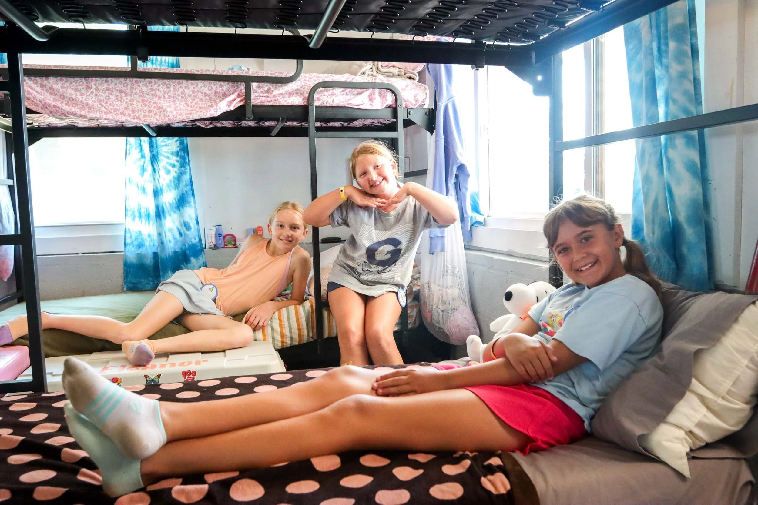 Three girls relaxing on their bunks in their cabin.