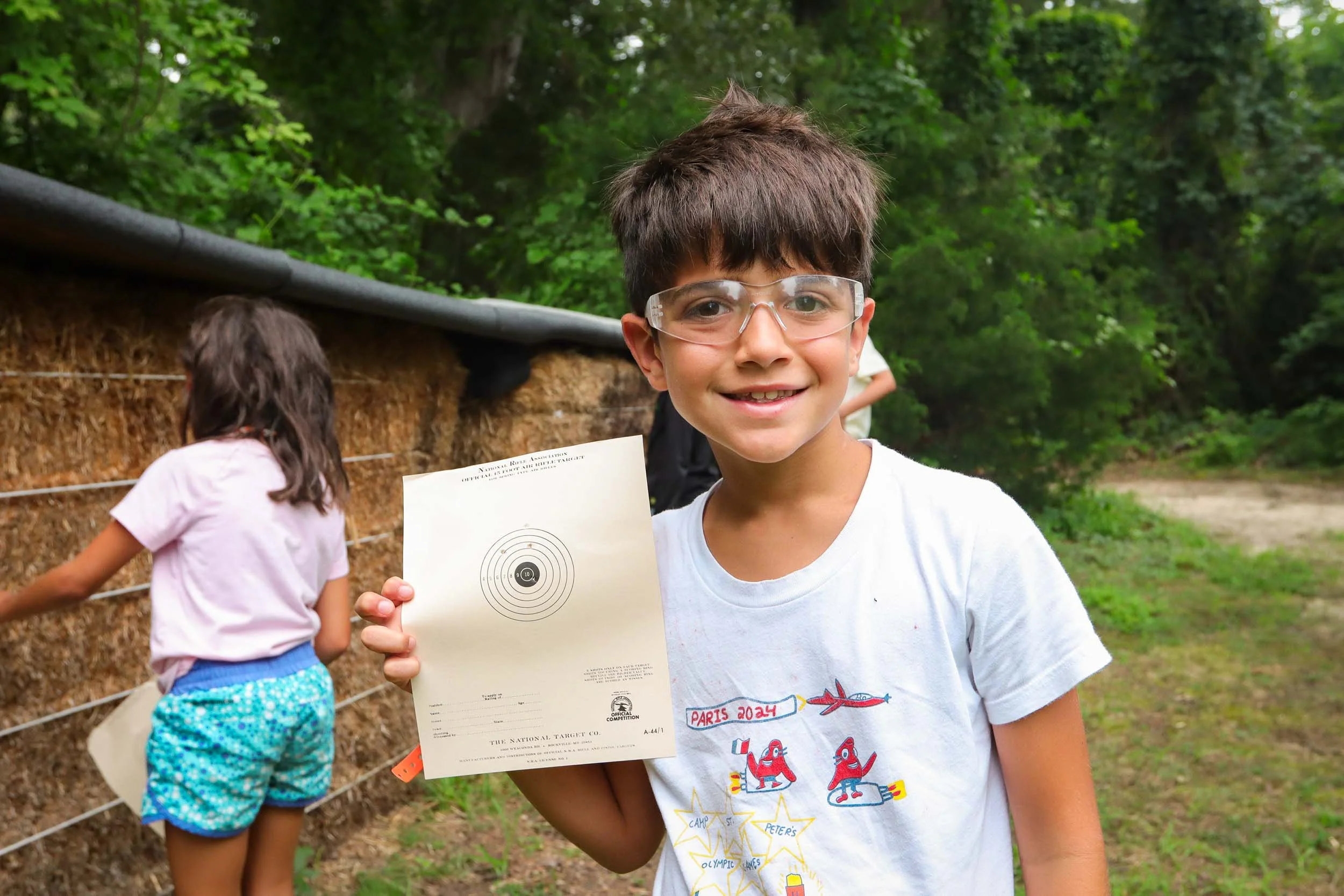 A young boy holding his bullseye target at the shooting range.