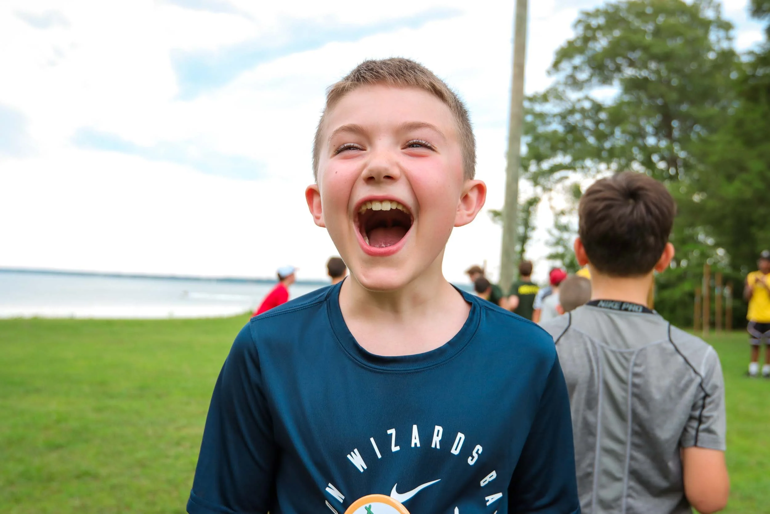 A young boy laughing outdoors.