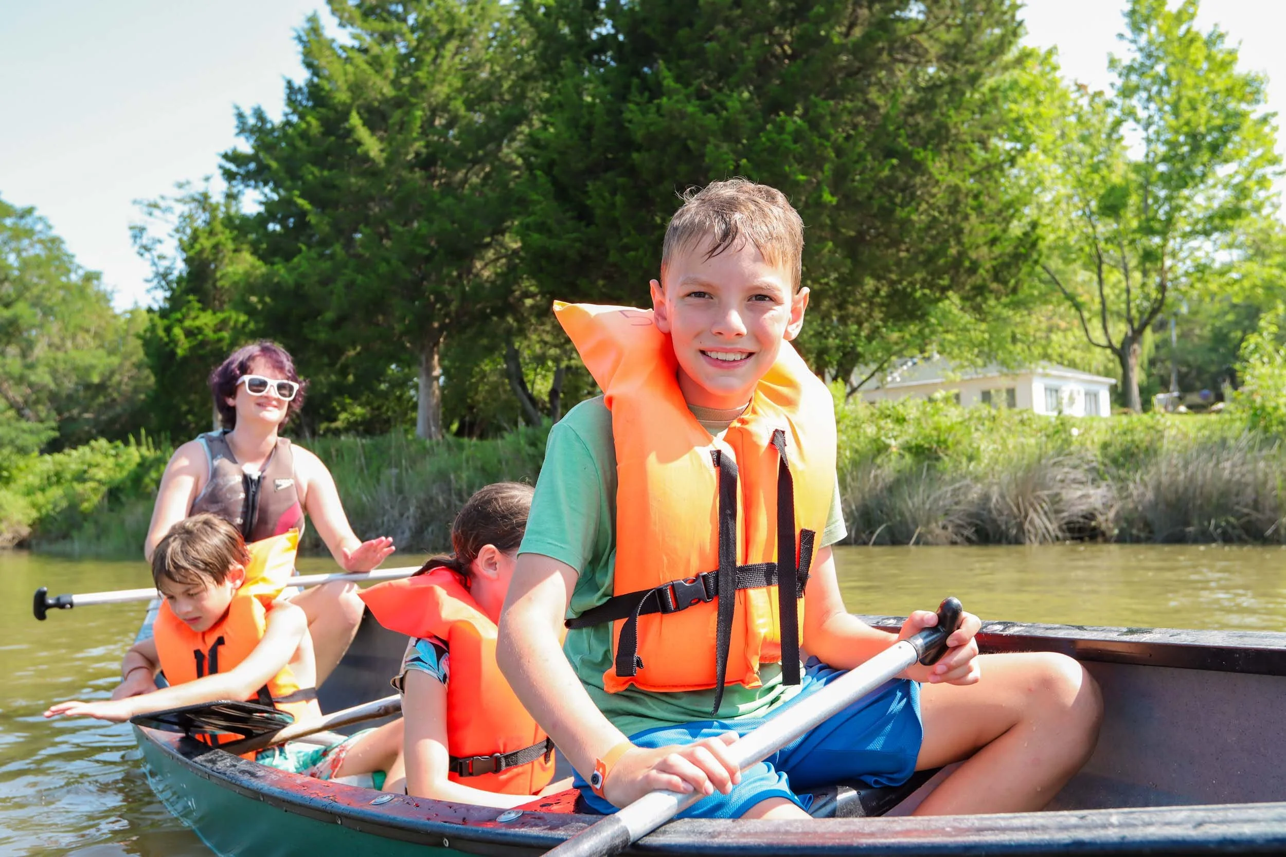 Campers wearing life jackets canoeing on the lake.