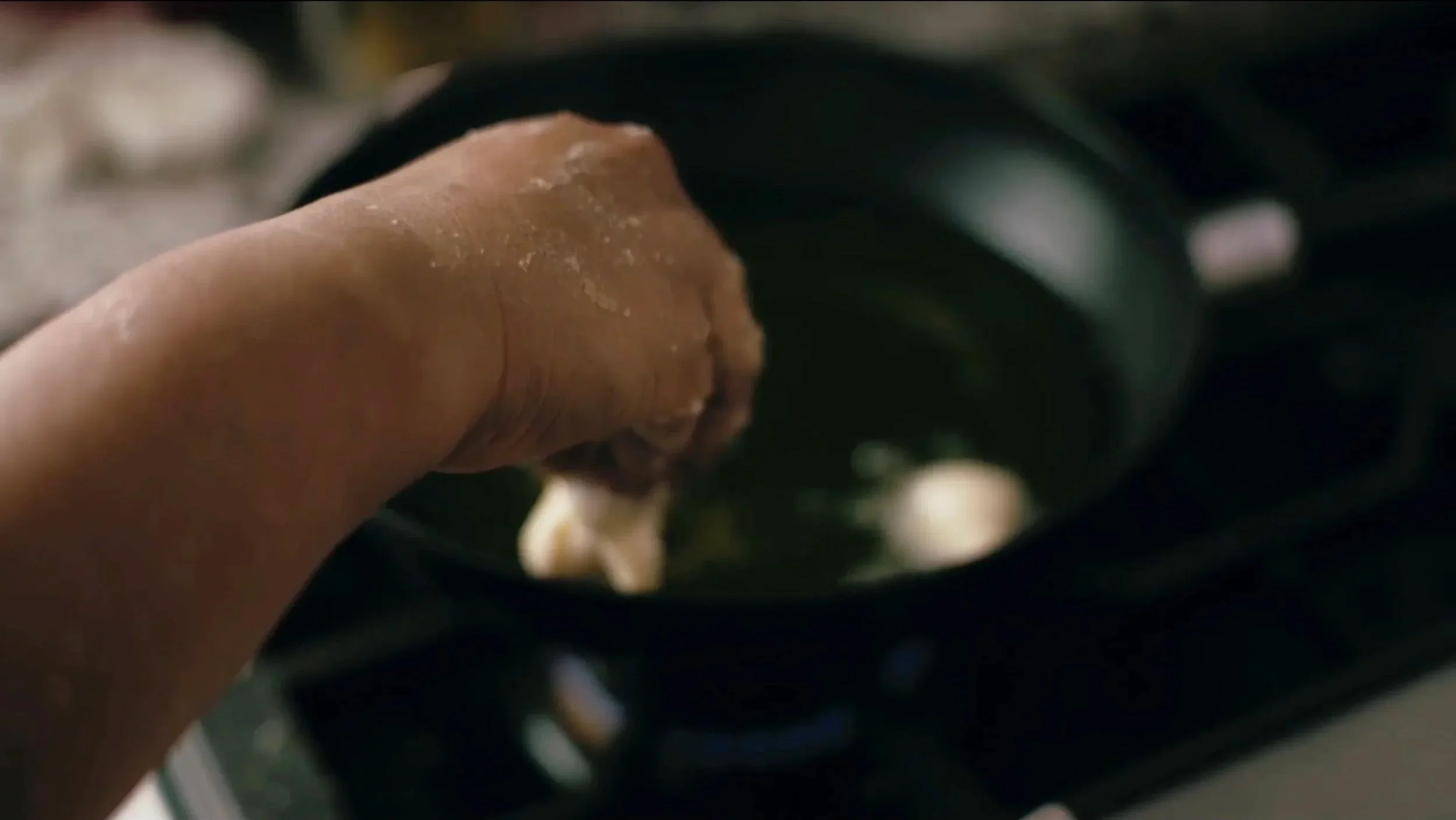 Close-up of a person’s finger touching or pressing a dark, smooth surface, possibly a device or machine, with blurred background.