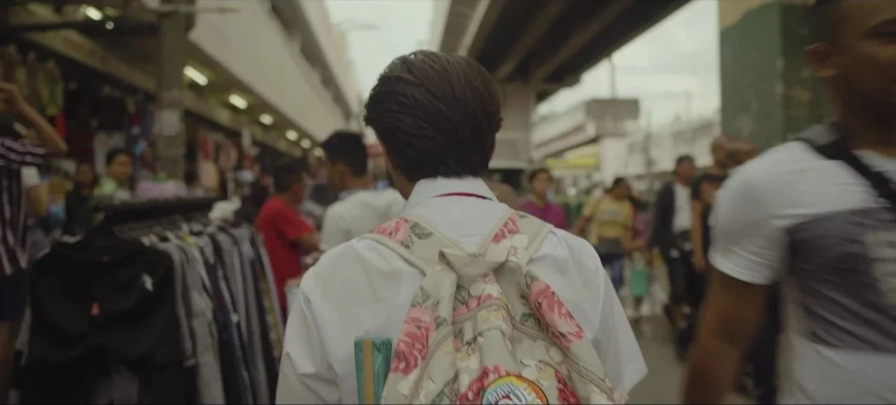 Person with a floral backpack walking through a busy marketplace.
