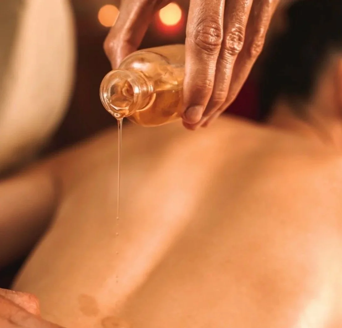 Close-up of an Abhyanga oil treatment with someone pouring onto a client's back.