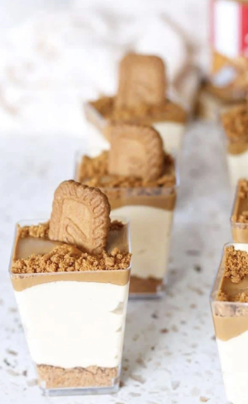 Dessert cups with layers of cream, chocolate, and crumbled cookies topped with a cookie piece.