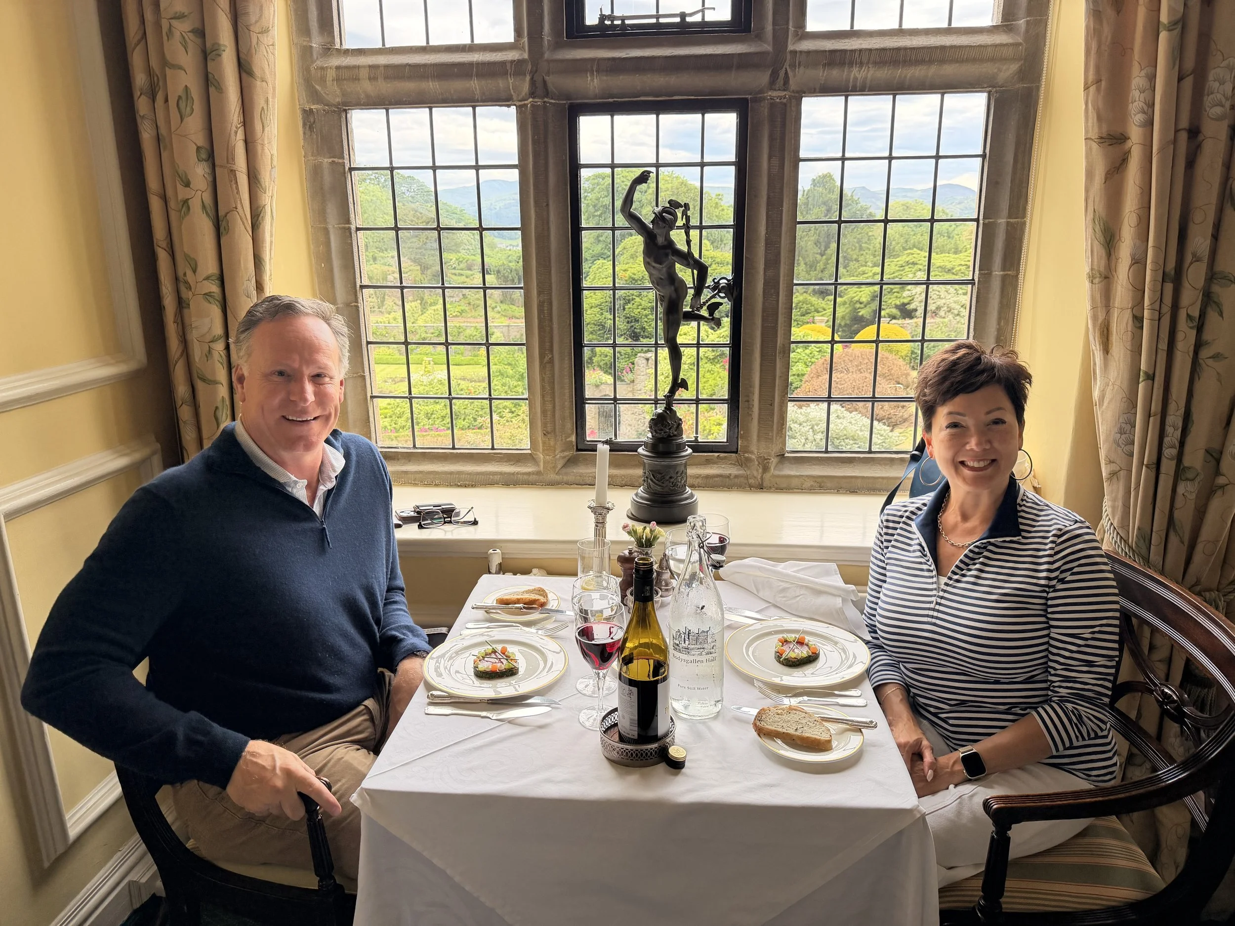 Couple at a window dinner table at Bodysgallen Hall with Conwy Castle in the distance