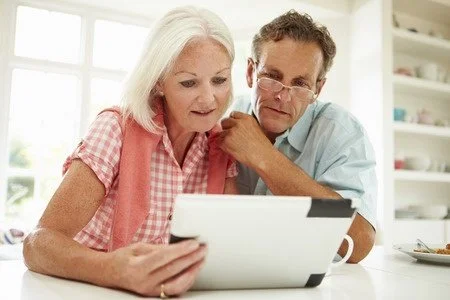 A woman and a man looking at a tablet together in a bright kitchen.