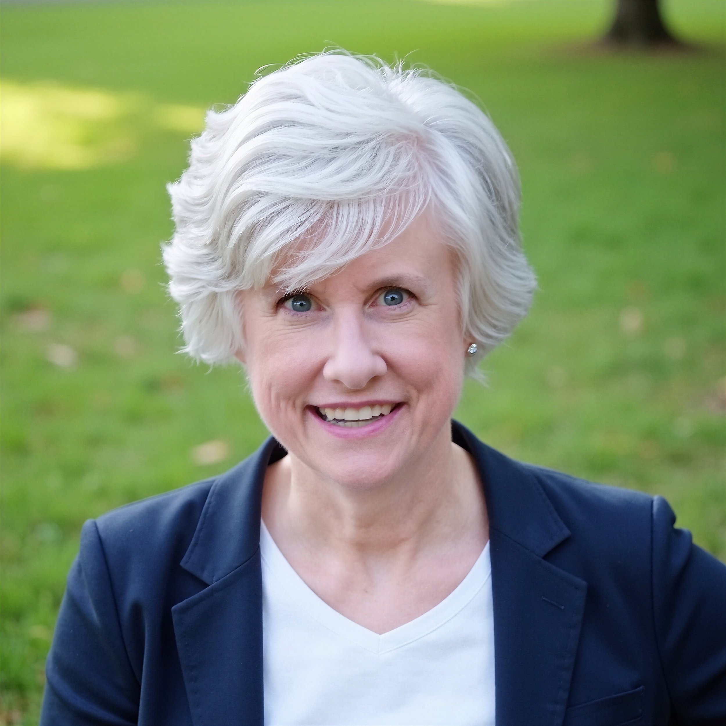 Cynthia Mead, founder of The Mead Law Firm, LLC, smiling and wearing a navy blazer over a white top, outdoors with green grass in the background.