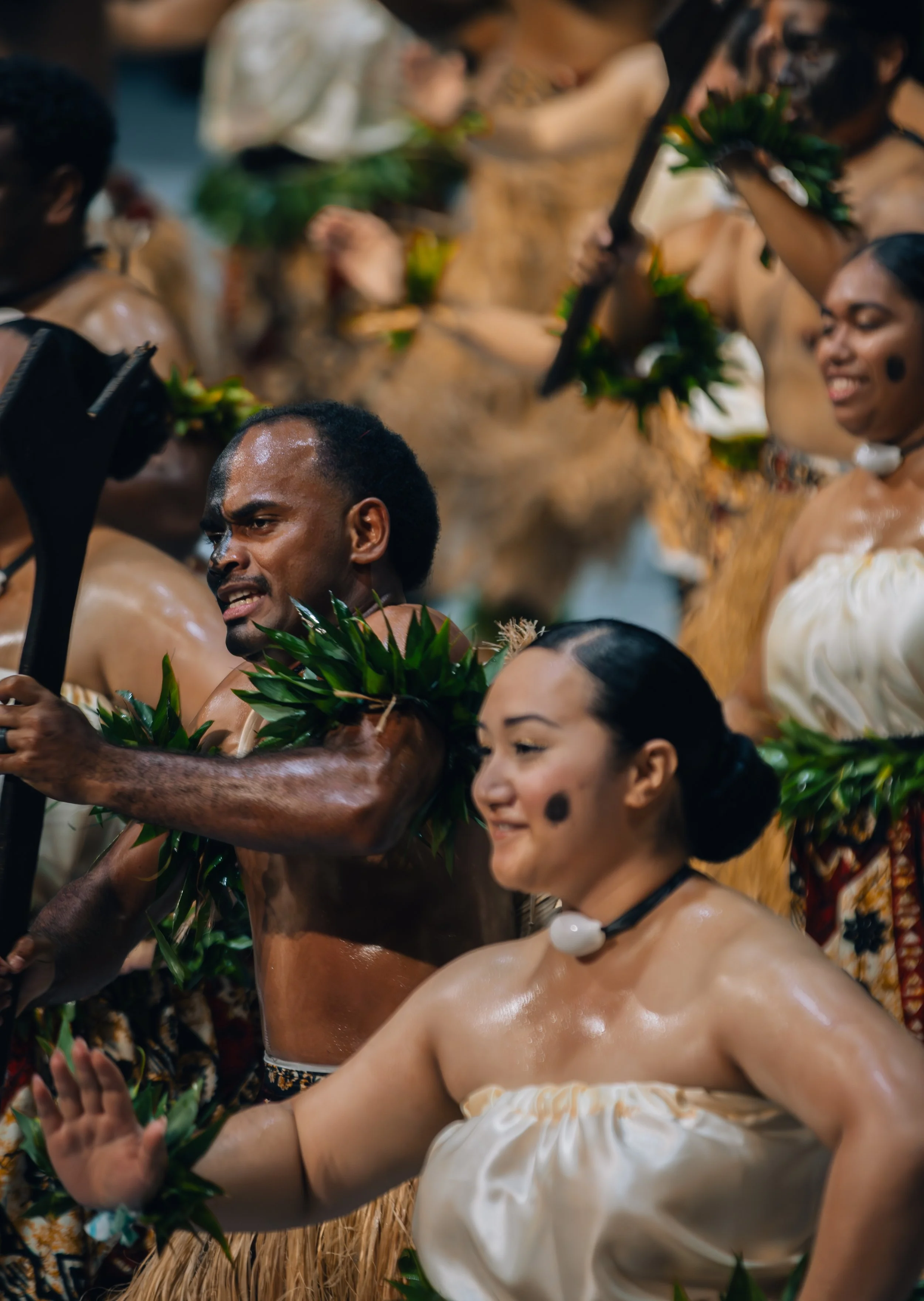 People participating in a traditional cultural dance or ceremony, wearing costumes with natural elements like leaves and beads.