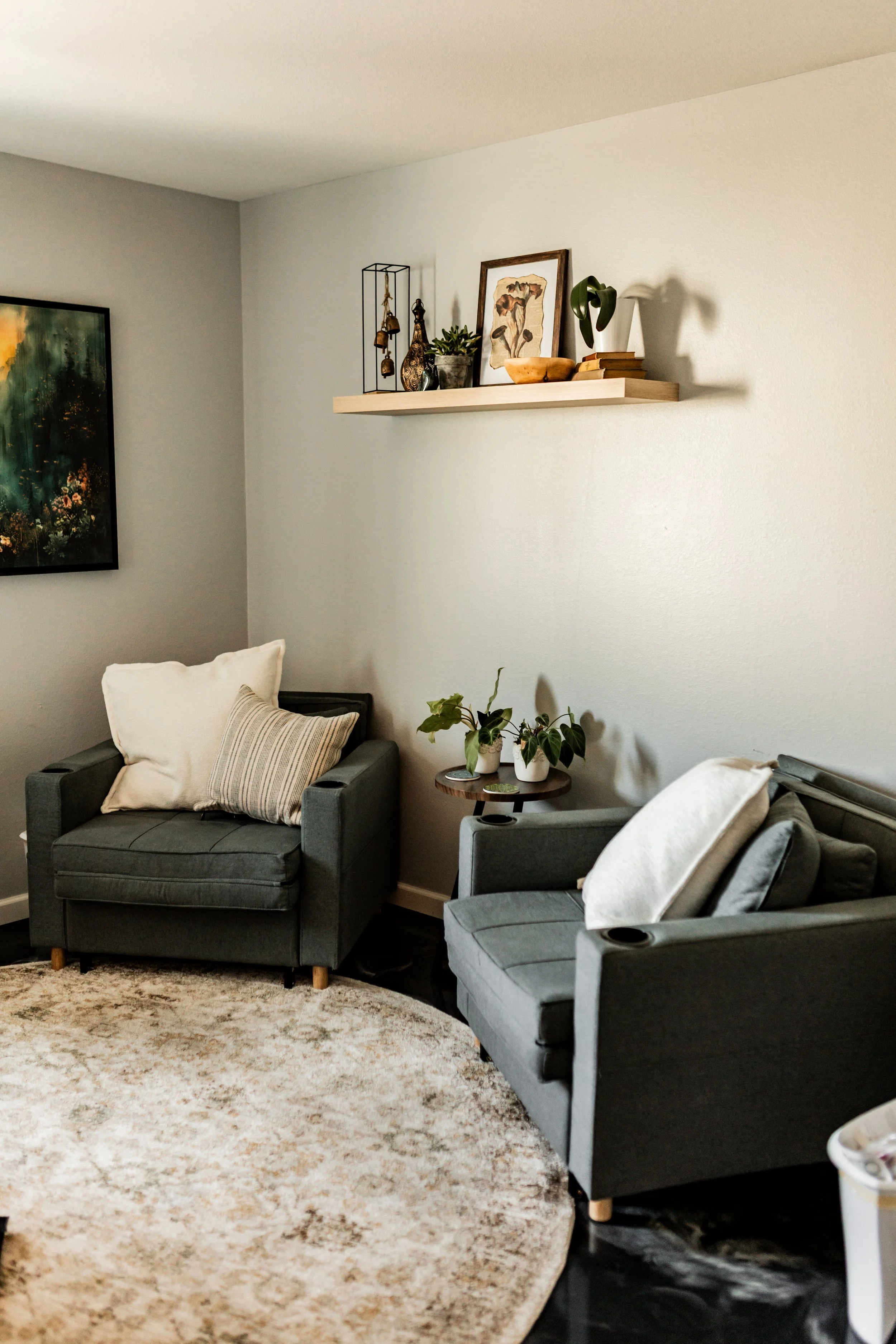 Katie Tyrrell’s office with two gray armchairs, a patterned rug, plants, and a wall shelf.