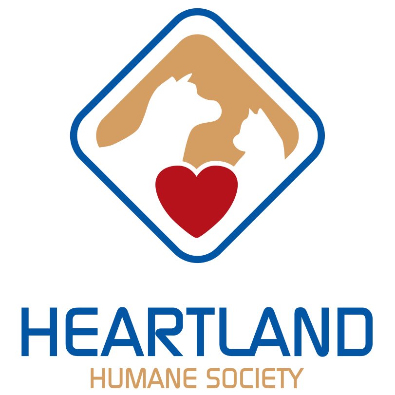 Logo of Heartland Humane Society featuring the silhouettes of a dog and a cat within a diamond shape, with a red heart in the center, and the text 'HEARTLAND' in blue and 'HUMANE SOCIETY' in tan beneath.
