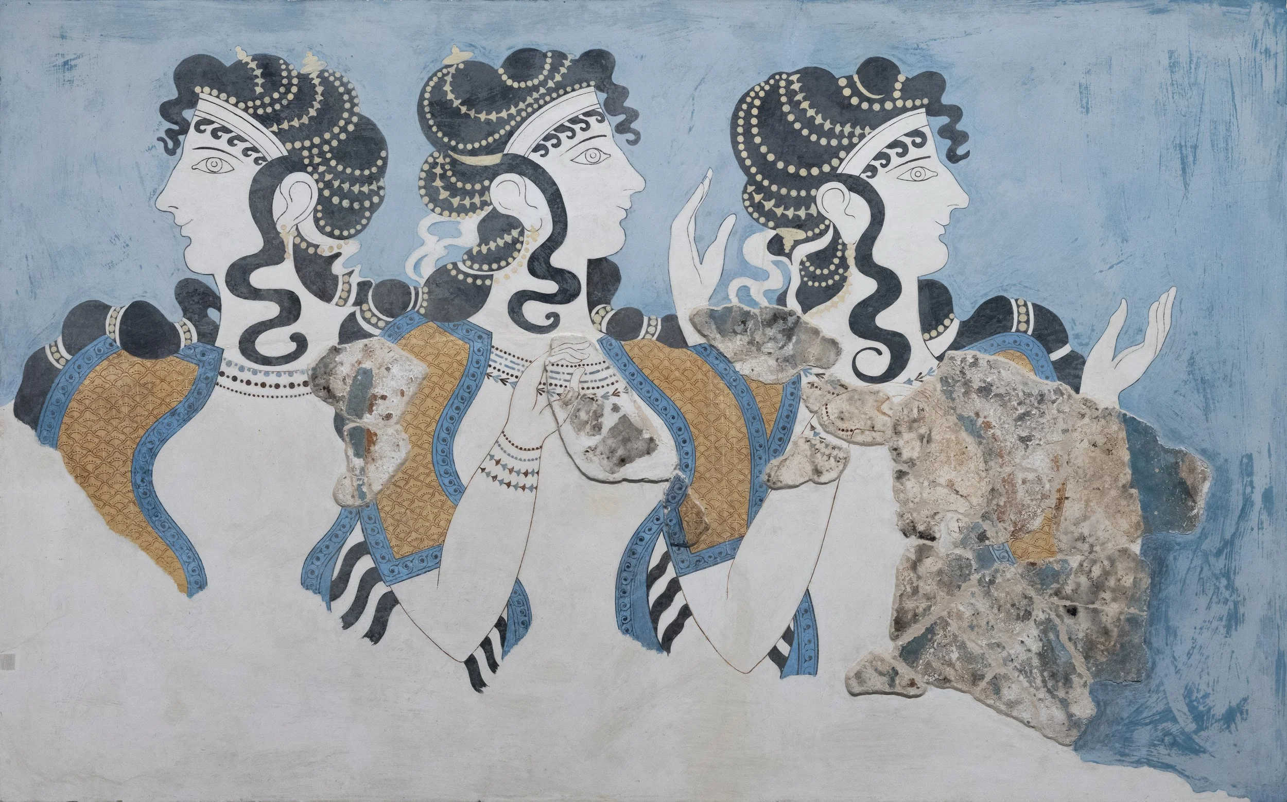 Ancient mural painting of four women with black curly hair, ornate clothing, and jewelry, holding hands and gesturing, with some parts damaged.