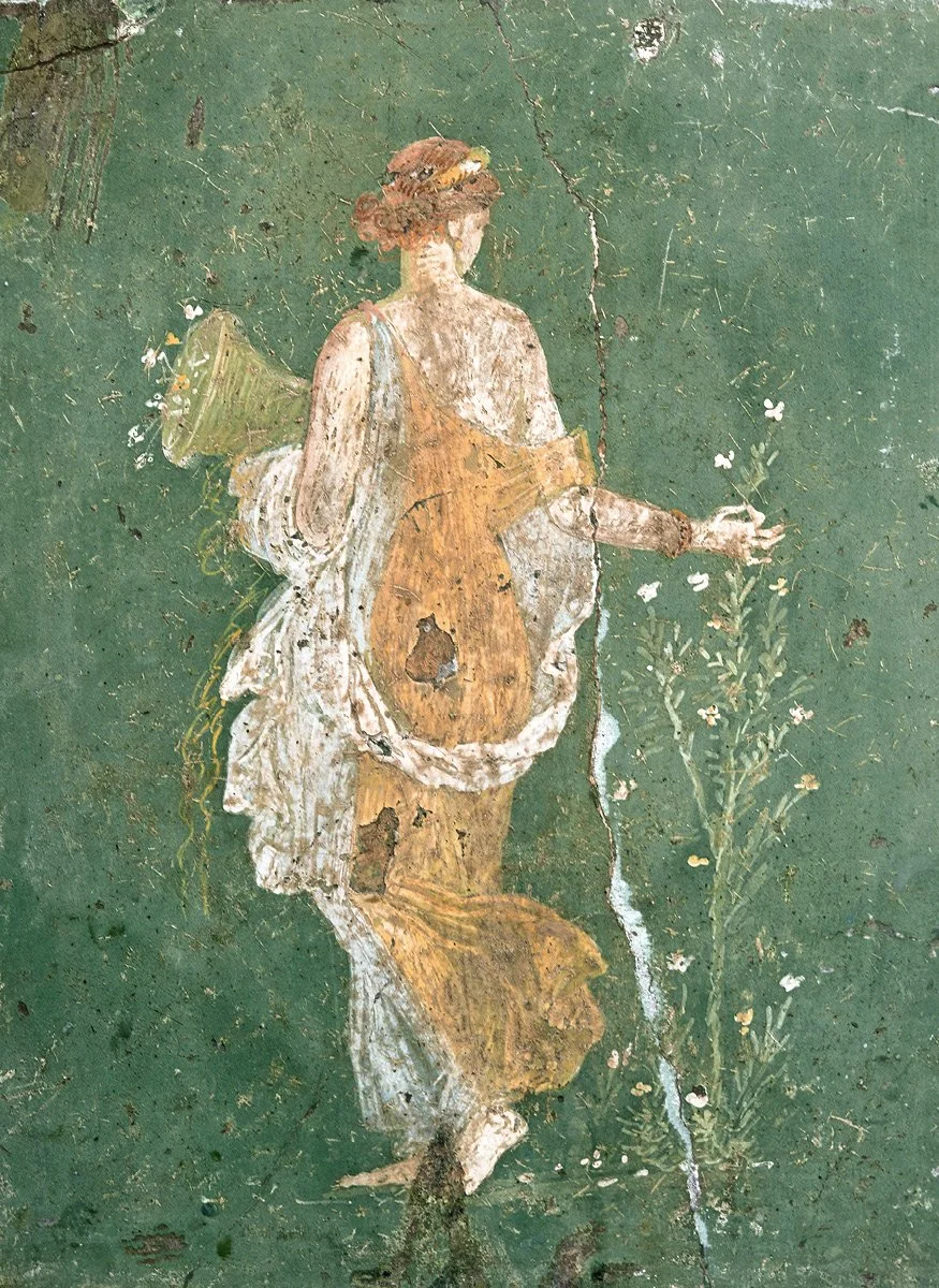Faded mural of a woman with curly hair, wearing a dress with an apron, holding a pitcher and a flower, on a green wall.